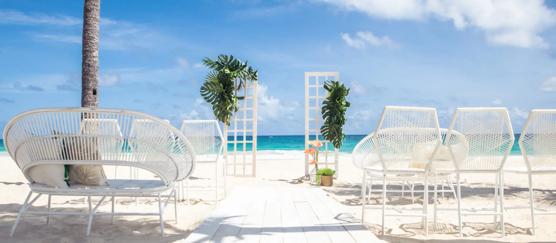 Beachfront wedding ceremony setup with white chairs and floral arches at Hard Rock Riviera Maya