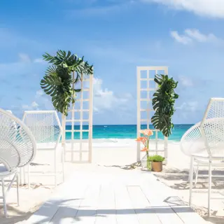 Beachfront wedding ceremony setup with white chairs and floral arches at Hard Rock Riviera Maya