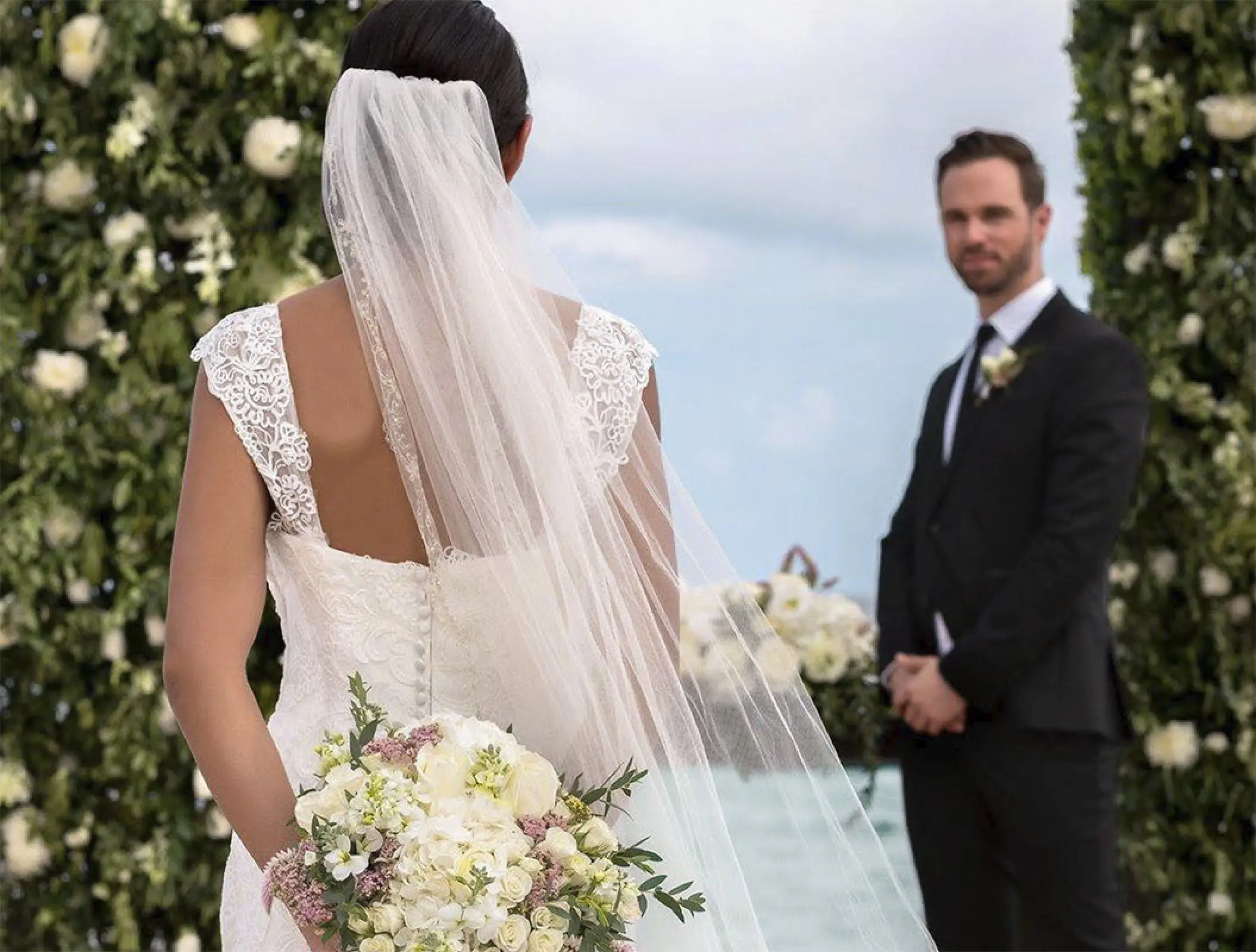 Bride and groom standing between floral pillars for a wedding ceremony at Haven Riviera Cancun, Riviera Maya