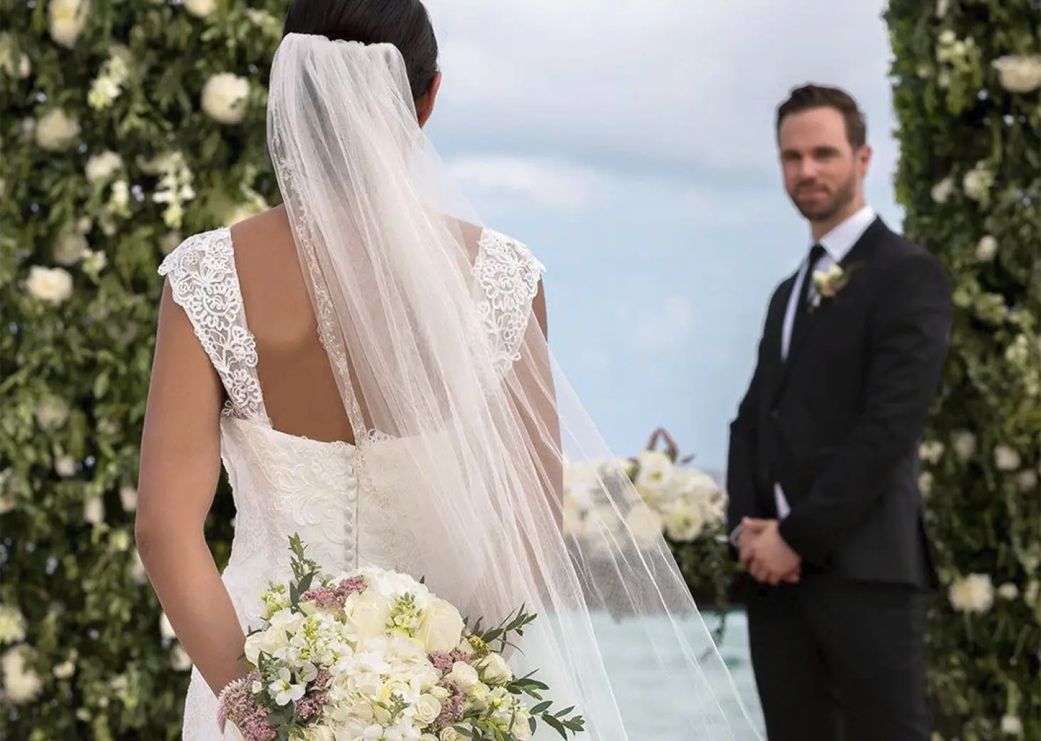 Bride and groom standing between floral pillars for a wedding ceremony at Haven Riviera Cancun, Riviera Maya