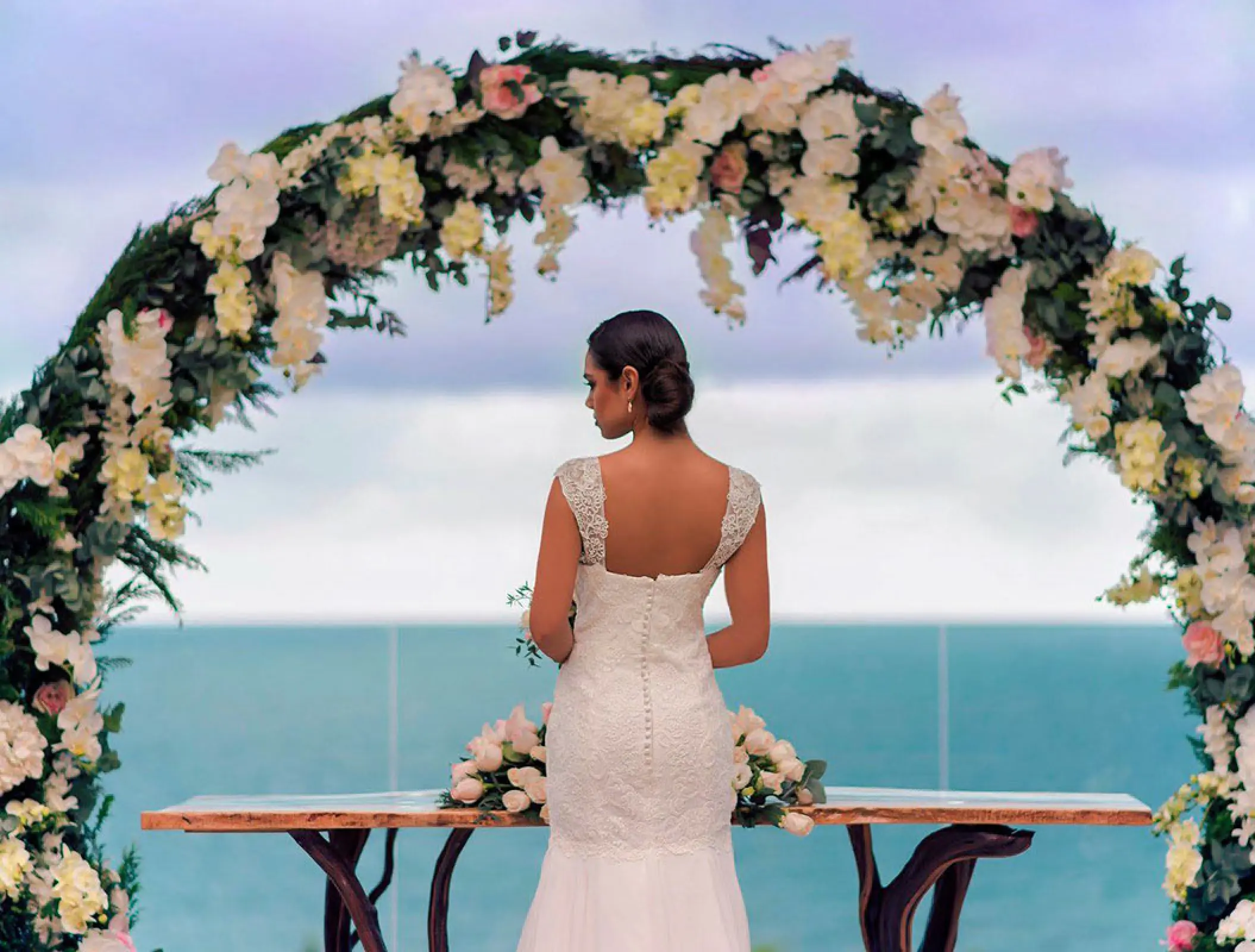 Bride standing under a floral arch for a terrace wedding ceremony at Haven Riviera Cancun, Riviera Maya
