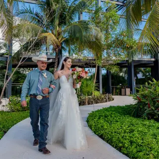 Bride walking down the aisle garden path with her father at Haven Riviera Cancun, Riviera Maya