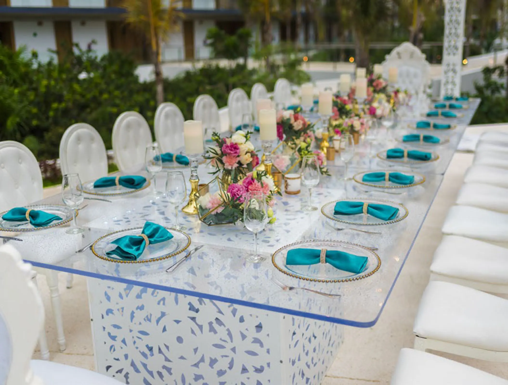 Long wedding reception table with turquoise napkins and floral centerpieces at Haven Riviera Cancun, Riviera Maya