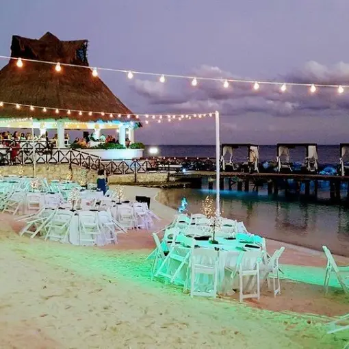 Beachfront wedding reception setup with string lights at Hard Rock Riviera Maya