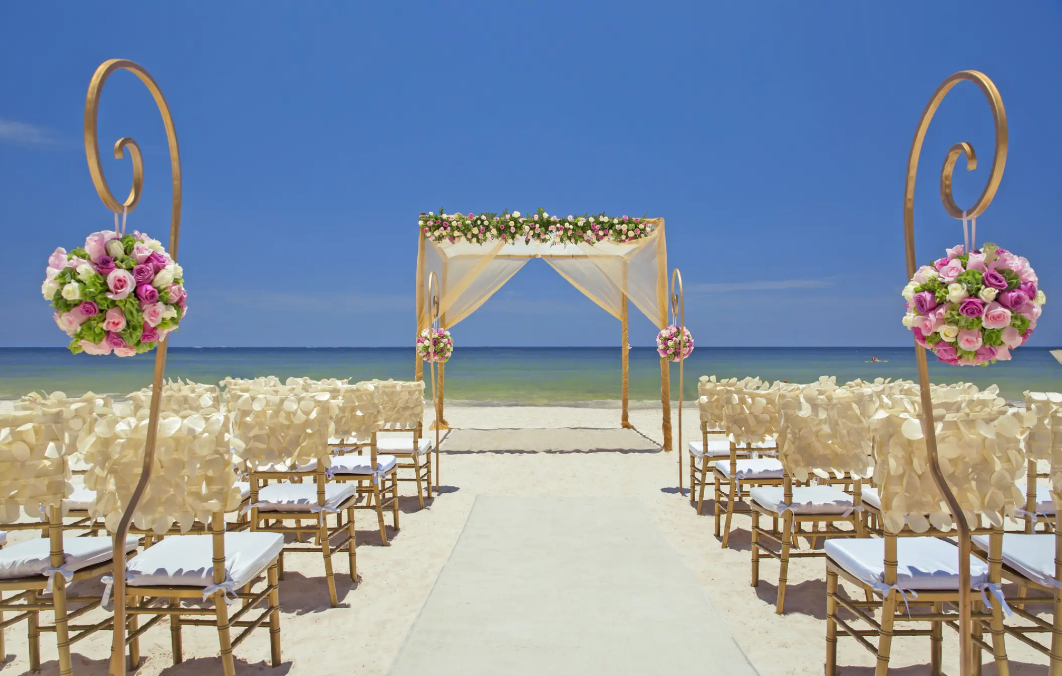 Beachfront wedding ceremony with a white huppah and floral pomanders at Royalton Hideaway Riviera Cancun