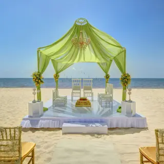 Green draped beach ceremony gazebo with a chandelier at Royalton Hideaway Riviera Cancun