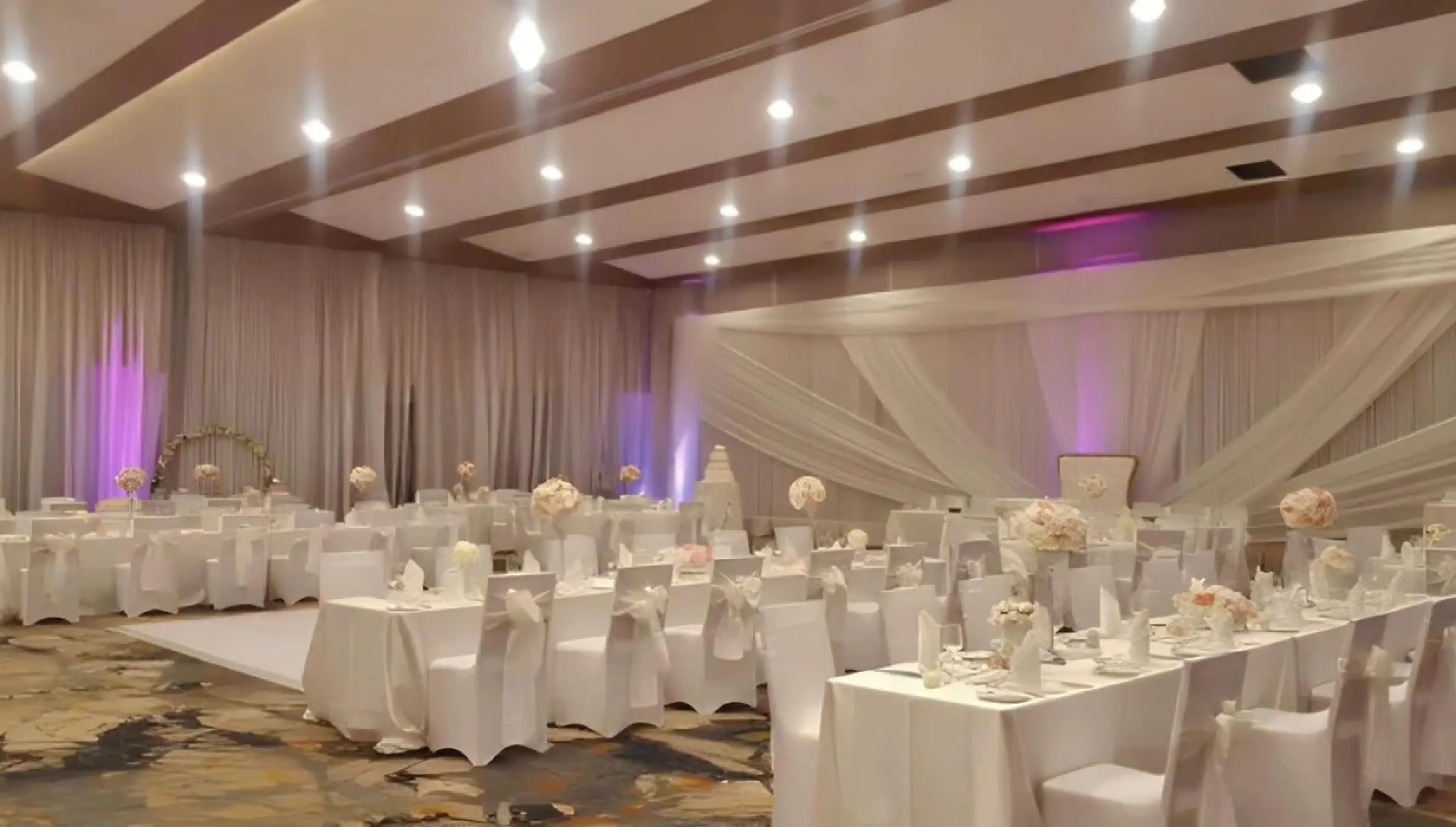 Indoor ballroom wedding reception with white linens and draped fabric at Royalton Hideaway Negril, Negril