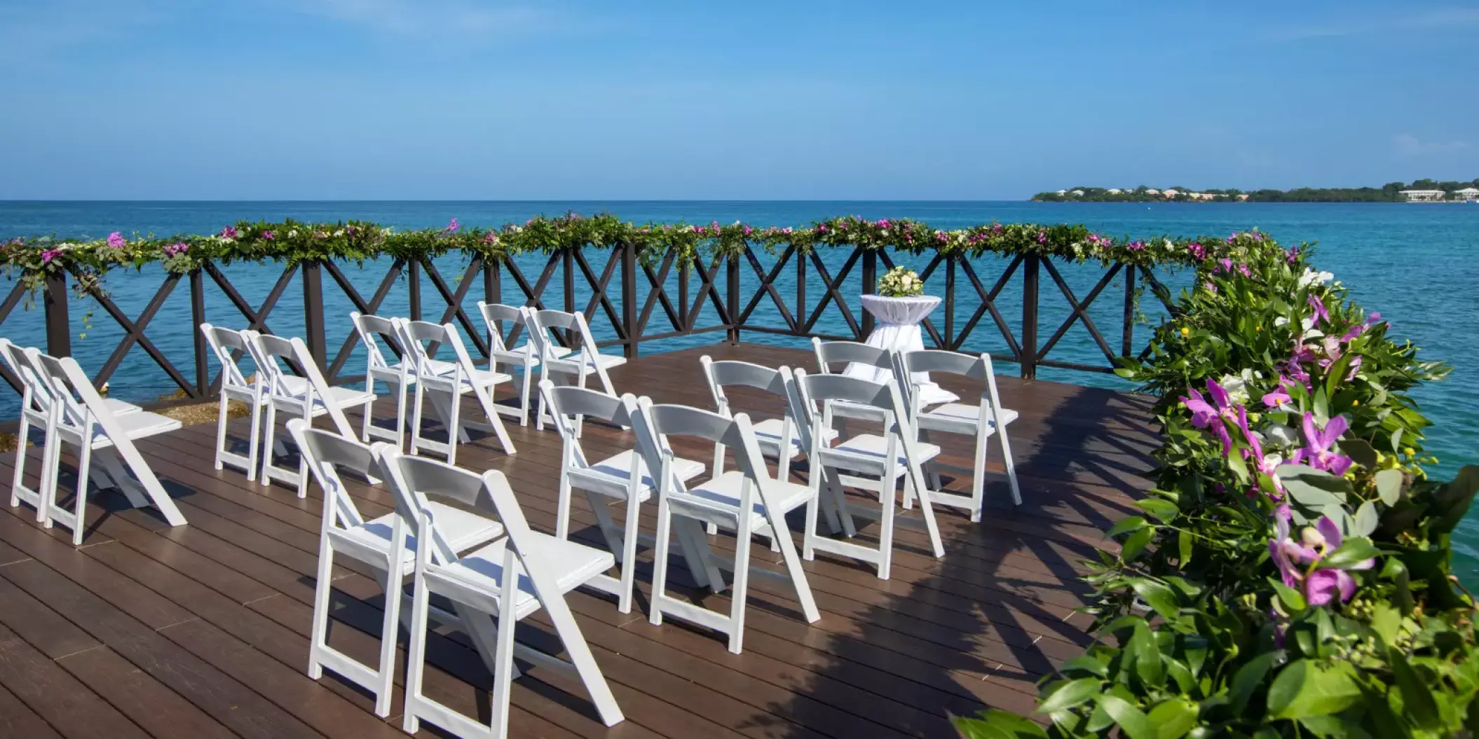 Ocean pier wedding ceremony setup with white chairs at Royalton Hideaway Negril
