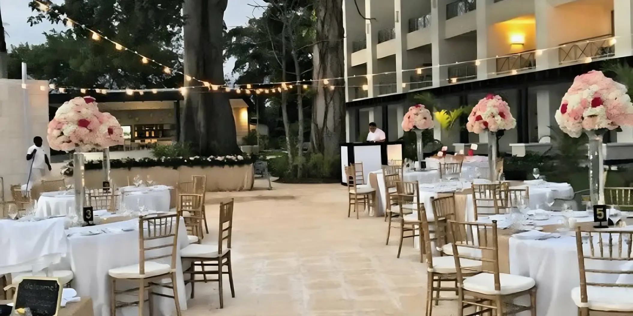 Outdoor wedding reception with floral centerpieces and string lights at Royalton Hideaway, Negril