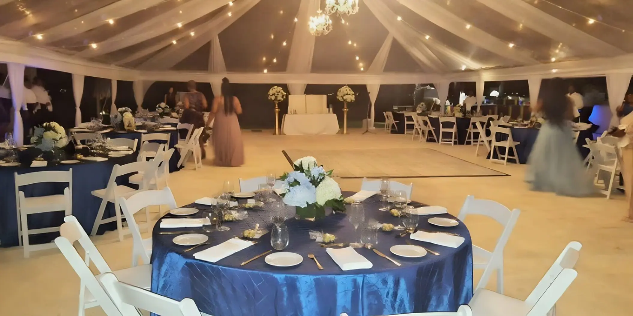 Wedding reception under a draped tent with blue linens and string lights at Royalton Hideaway Negril