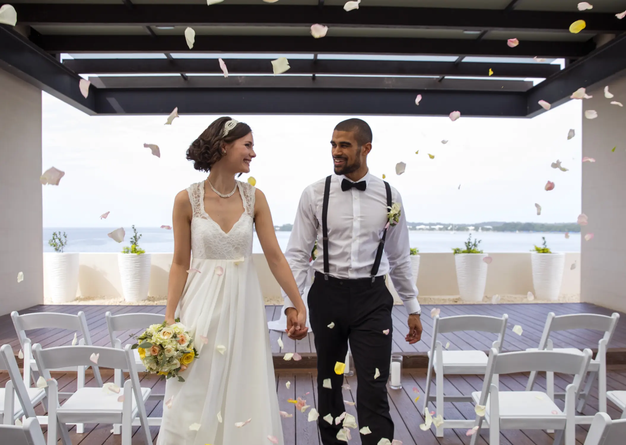 Bride and groom walking through falling petals on the Sky Terrace at Royalton Hideaway Negril, Negril