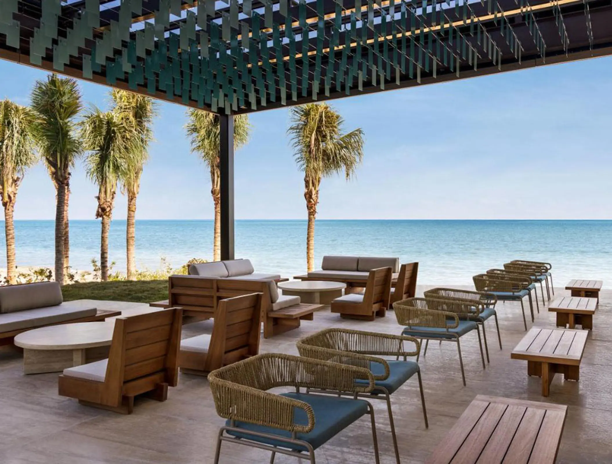 Shaded outdoor beach lounge area with wooden furniture at Hilton Cancun, Cancun
