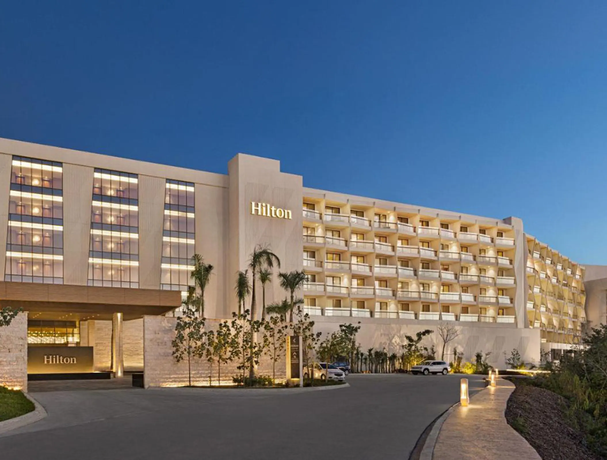Modern white exterior and entrance of Hilton Cancun at dusk, Cancun