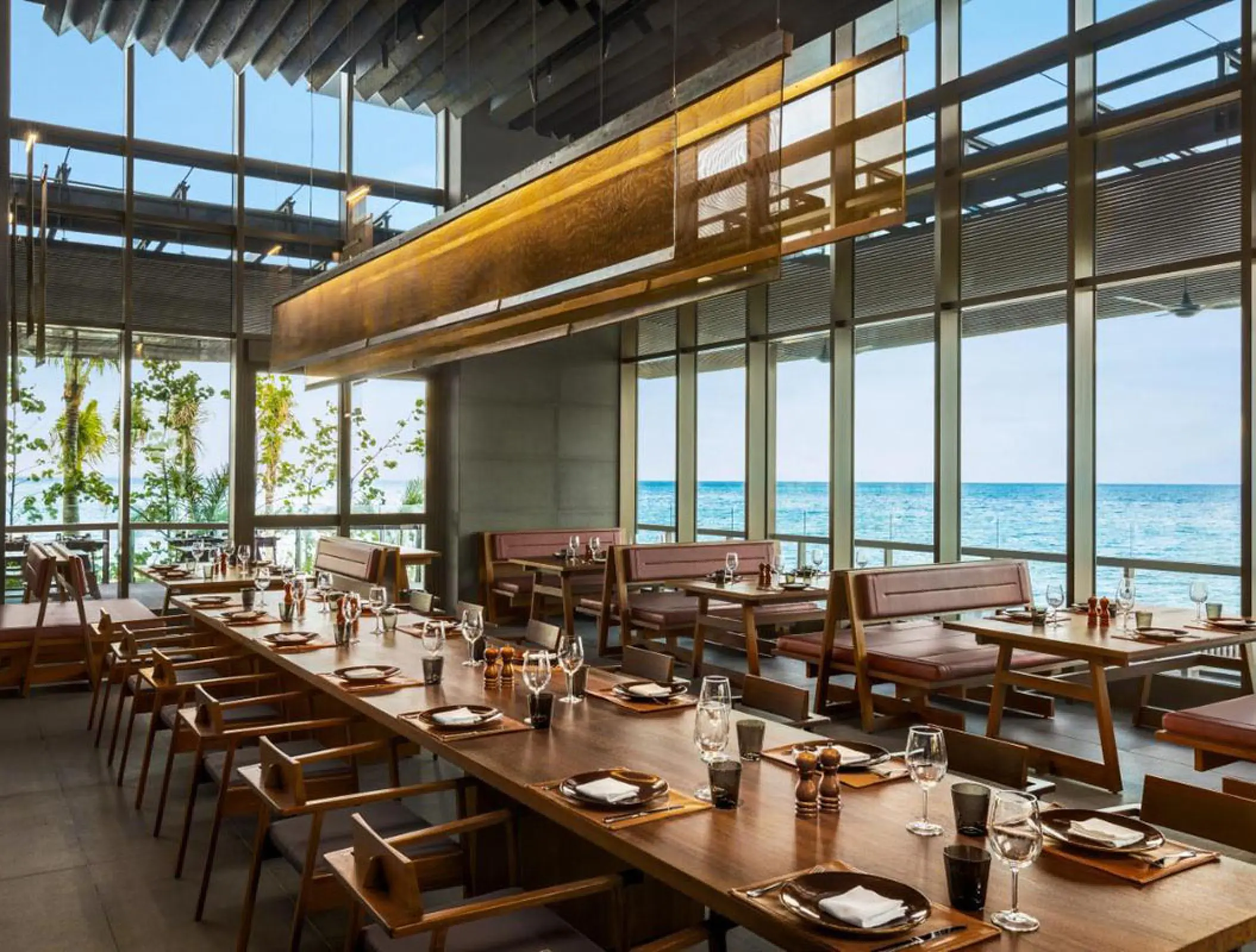 Modern ocean-view restaurant with long wooden dining tables at Hilton Cancun, Cancun