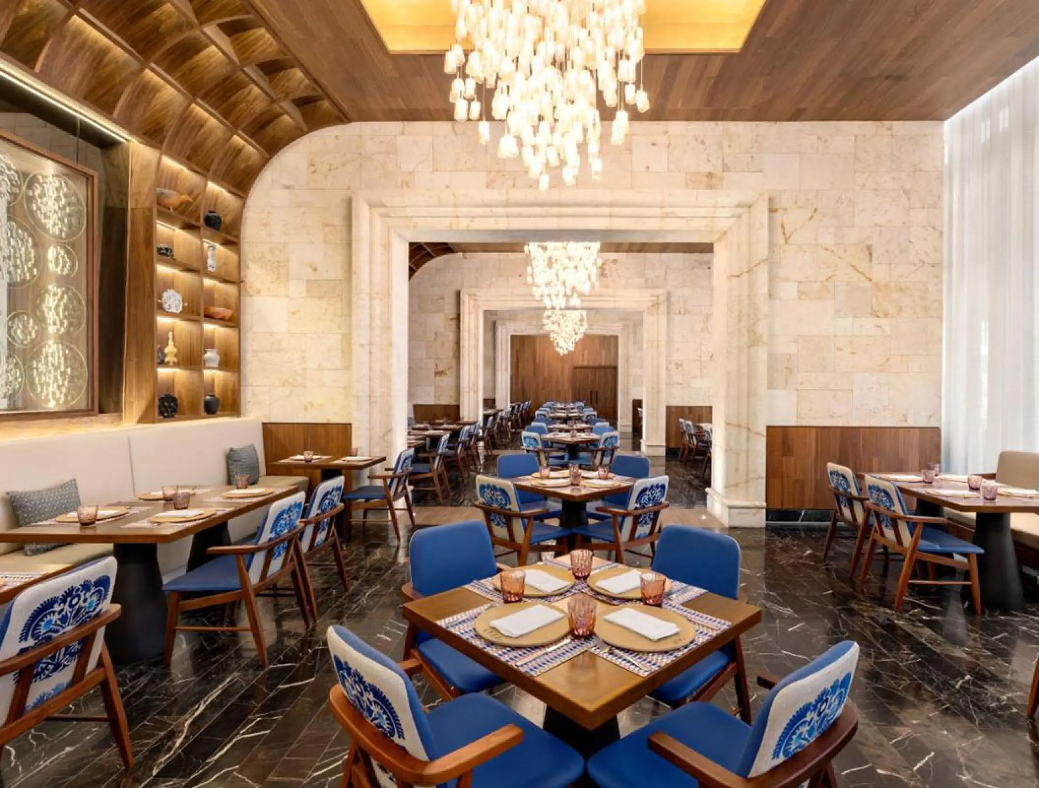 Modern restaurant dining room with blue chairs and stone walls at Hilton Cancun, Cancun
