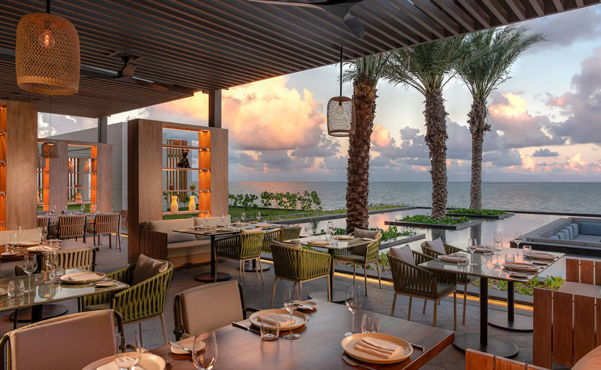 Outdoor restaurant terrace at Hilton Cancun overlooking the ocean at sunset