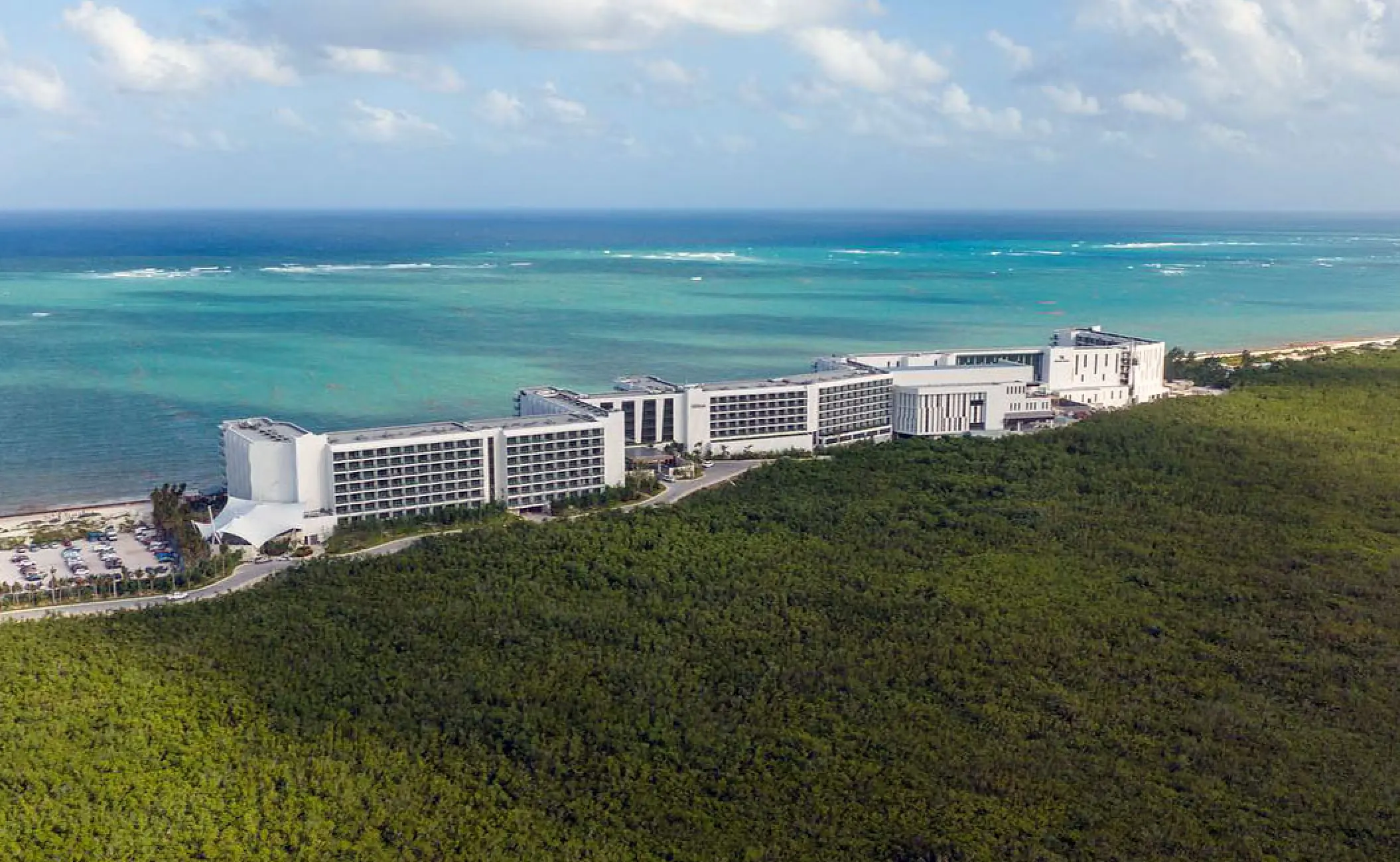 Aerial view of Hilton Cancun buildings between lush green jungle and turquoise ocean, Cancun