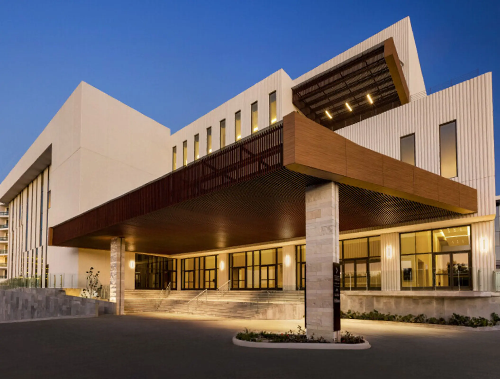 Hilton Cancun main entrance with modern white architecture and a wood-slatted portico at dusk, Cancun