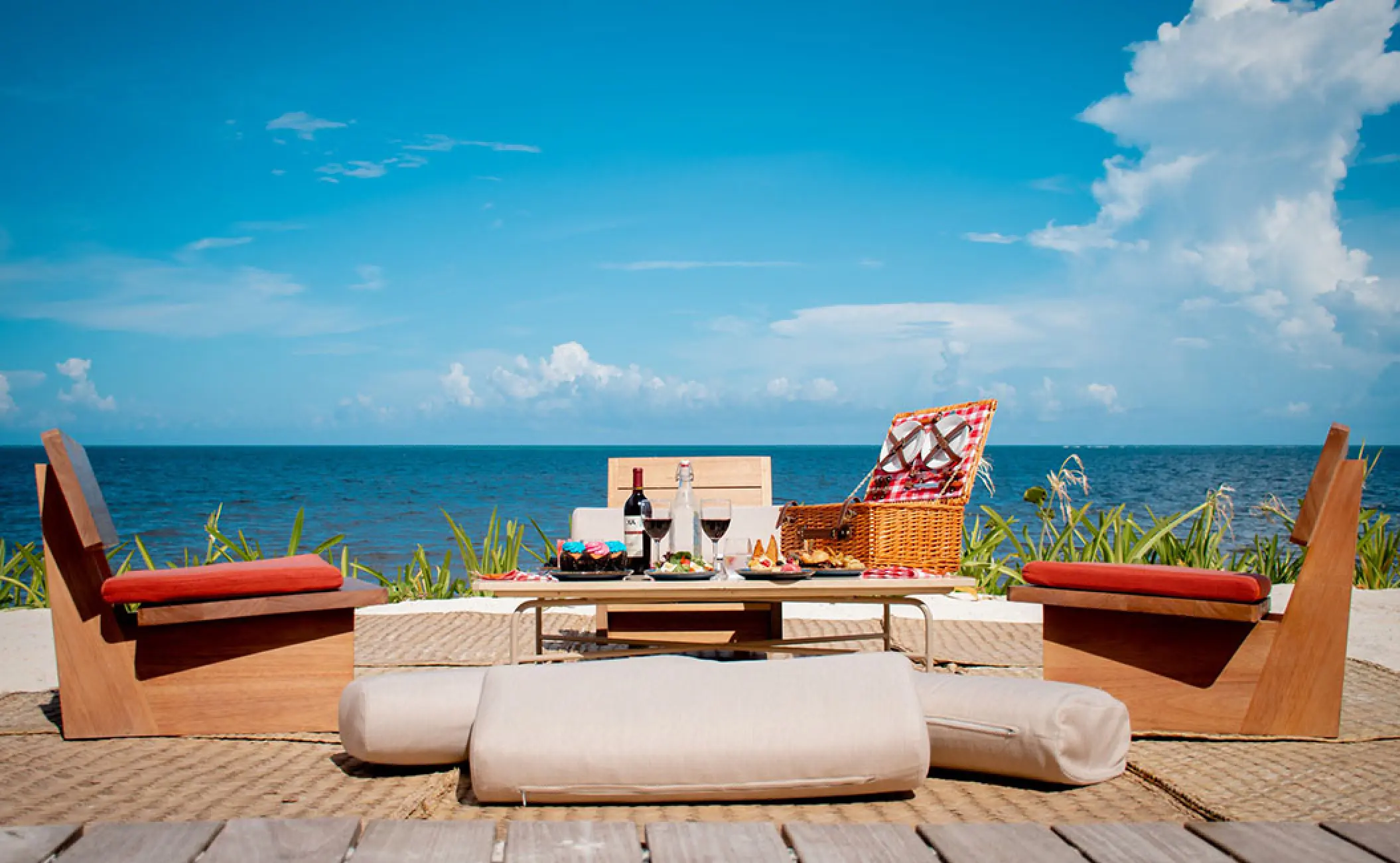 Private beach picnic setup with wine and a wicker basket at Hilton Cancun