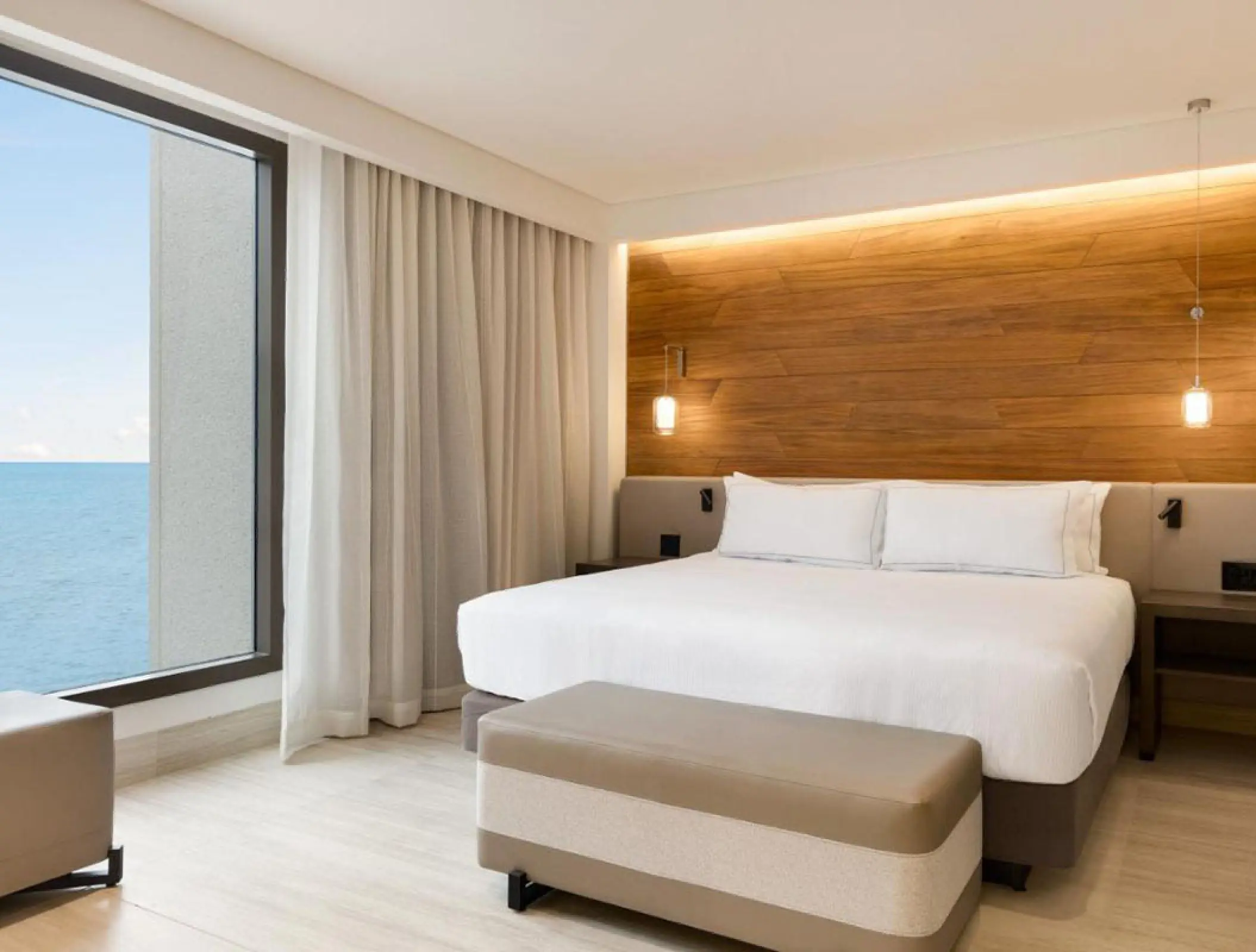 Ocean view room with wood paneling and white bedding at Hilton Cancun, Cancun