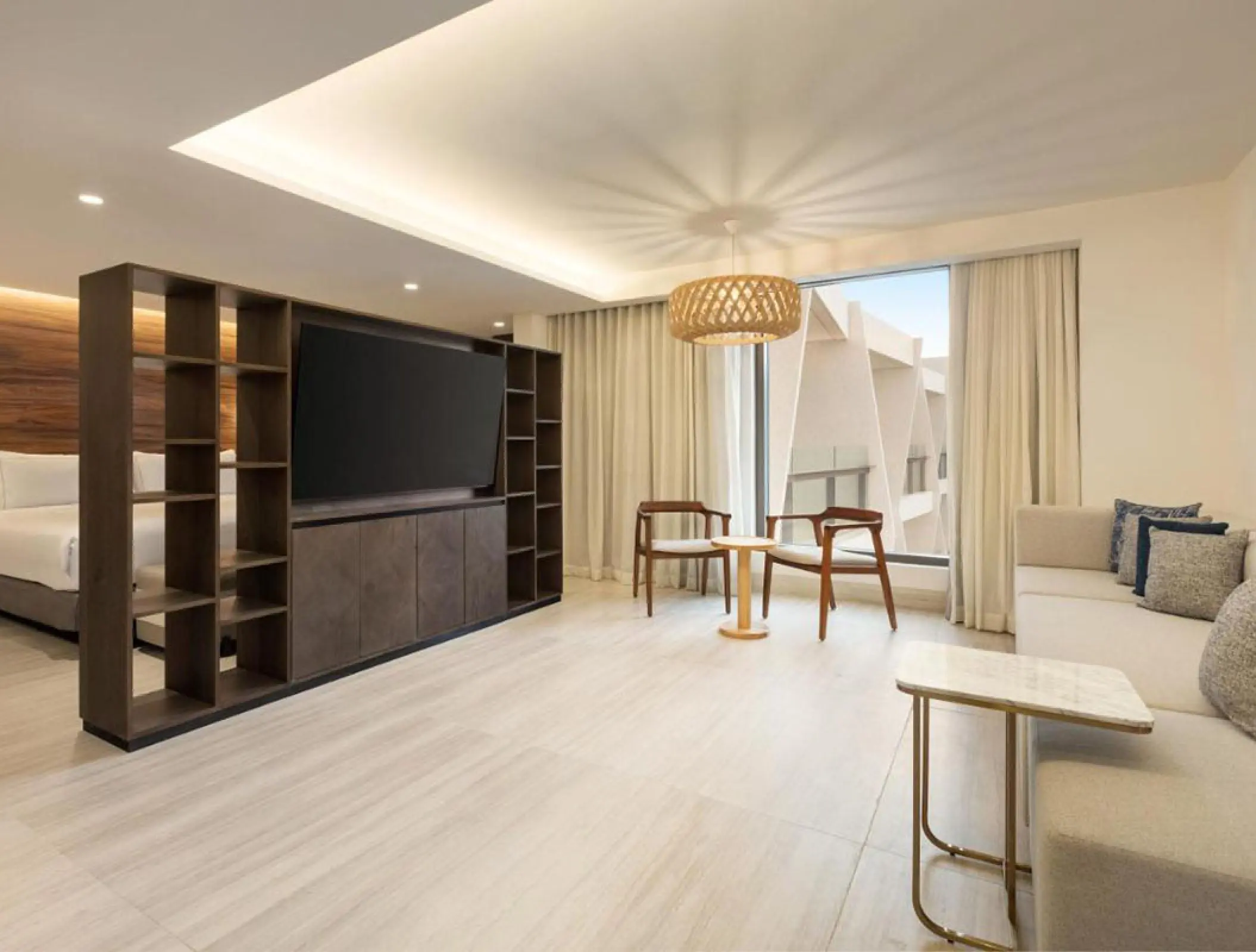 Modern suite living area with a large television and balcony window at Hilton Cancun, Cancun