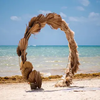 Circular dried palm leaf wedding ceremony arch on the beach at Hilton Cancun