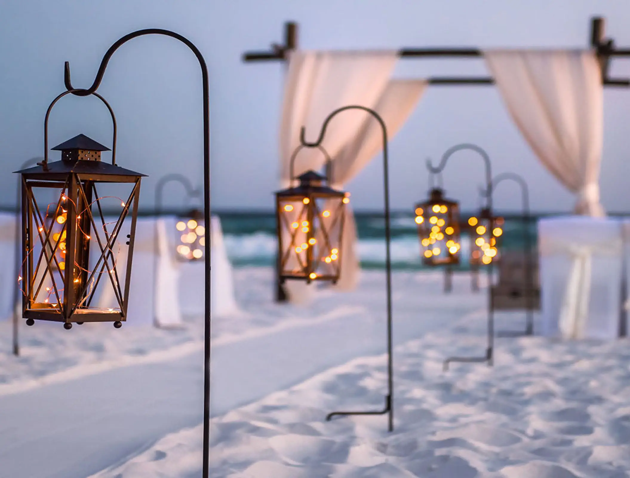 Lanterns on shepherd hooks lining a beach ceremony aisle at Hilton Cancun, Cancun