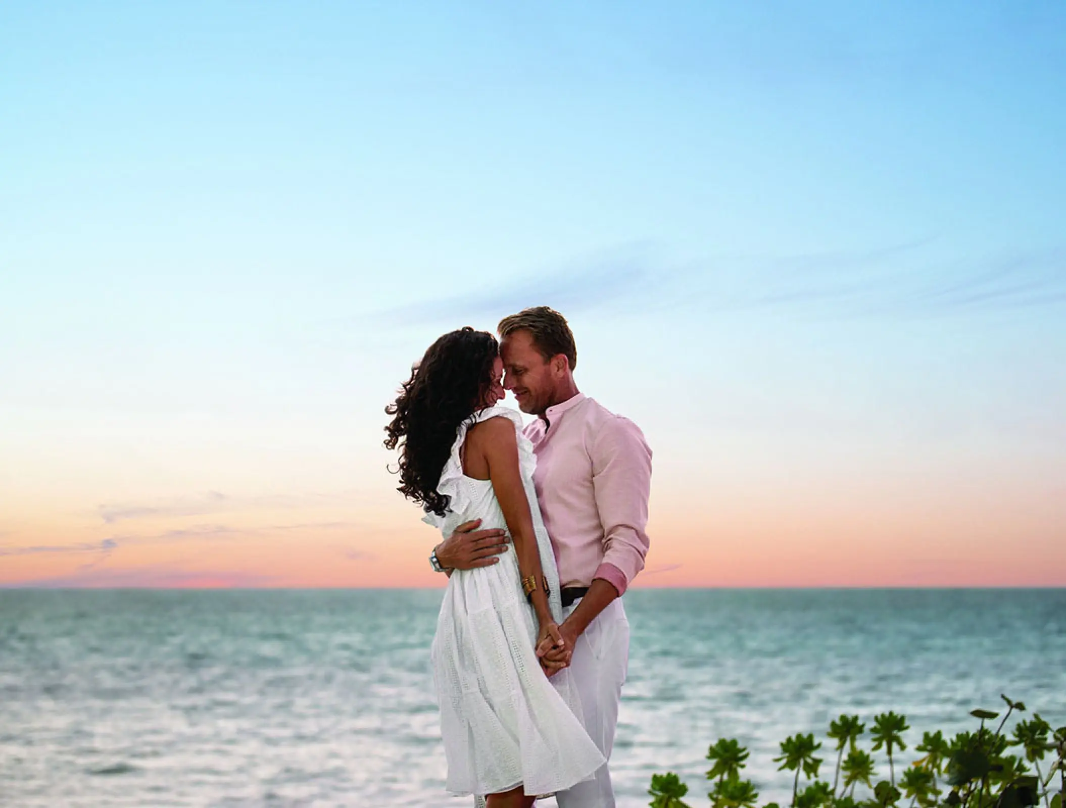 Couple embracing by the ocean at sunset at Hilton Cancun