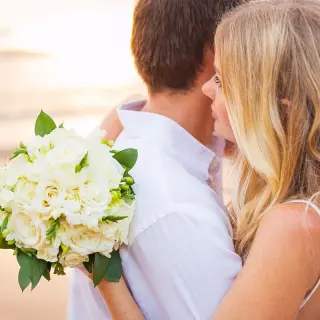 The bride holding a white rose bouquet while embracing the groom at Hilton Cancun