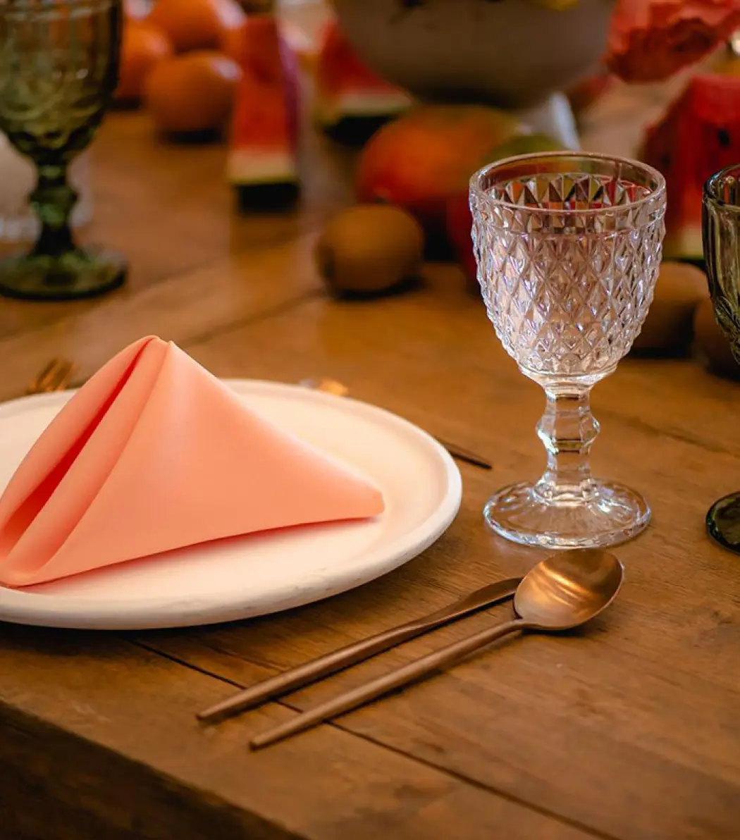 Table setting with peach napkin, crystal glassware, and tropical fruit at Hilton Cancun, Cancun