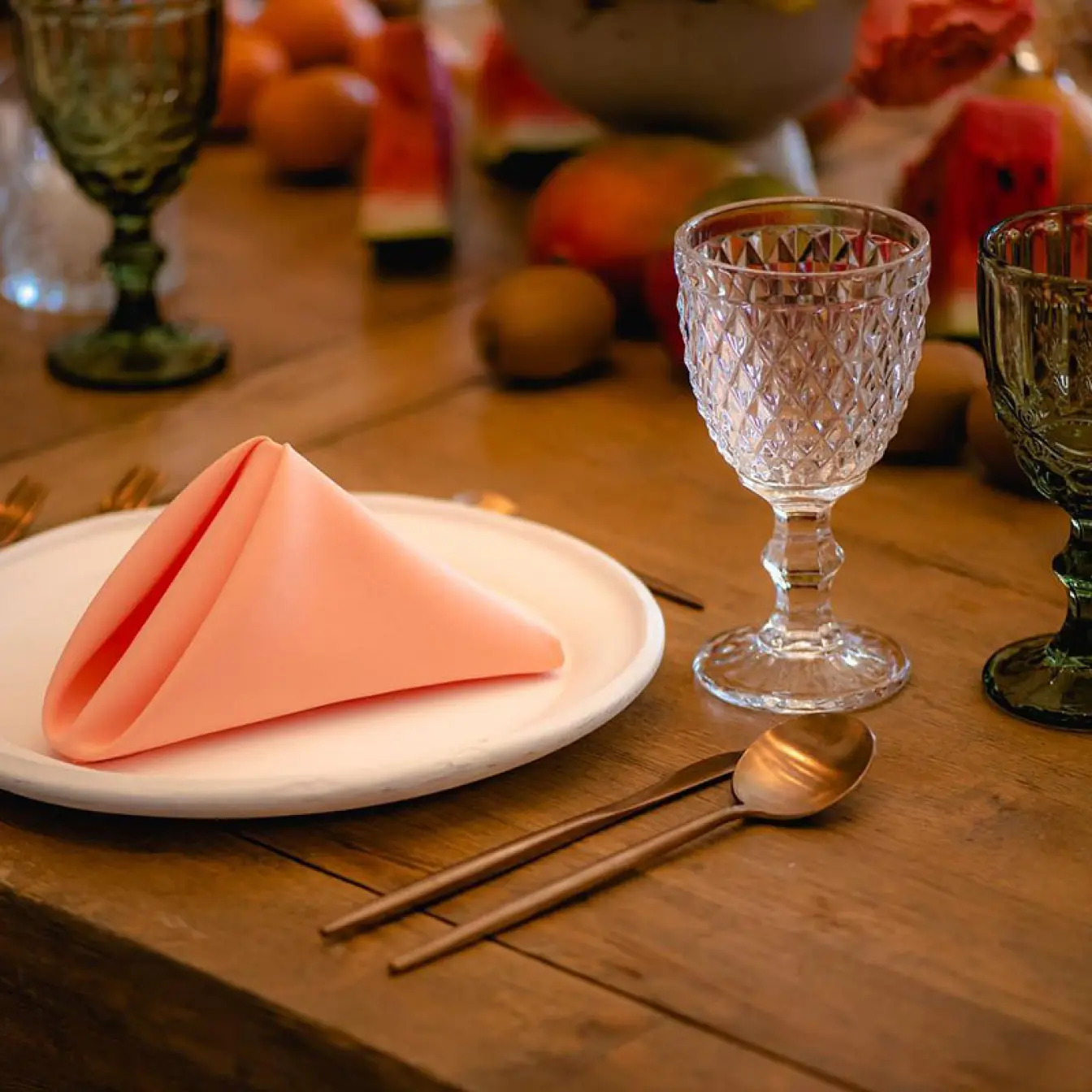 Table setting with peach napkin, crystal glassware, and tropical fruit at Hilton Cancun, Cancun