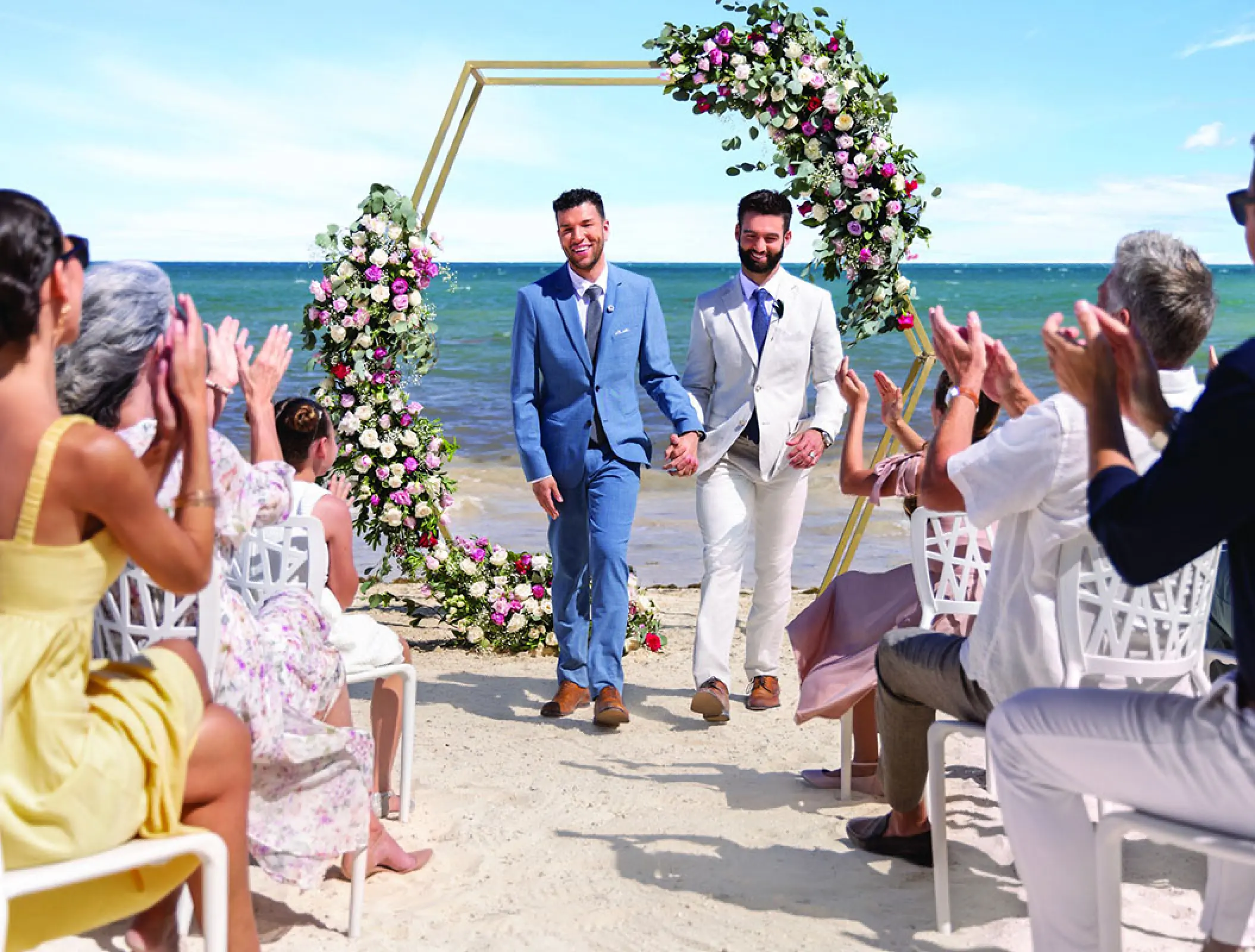 Same-sex couple walking down the aisle at a beach ceremony at Hilton Cancun