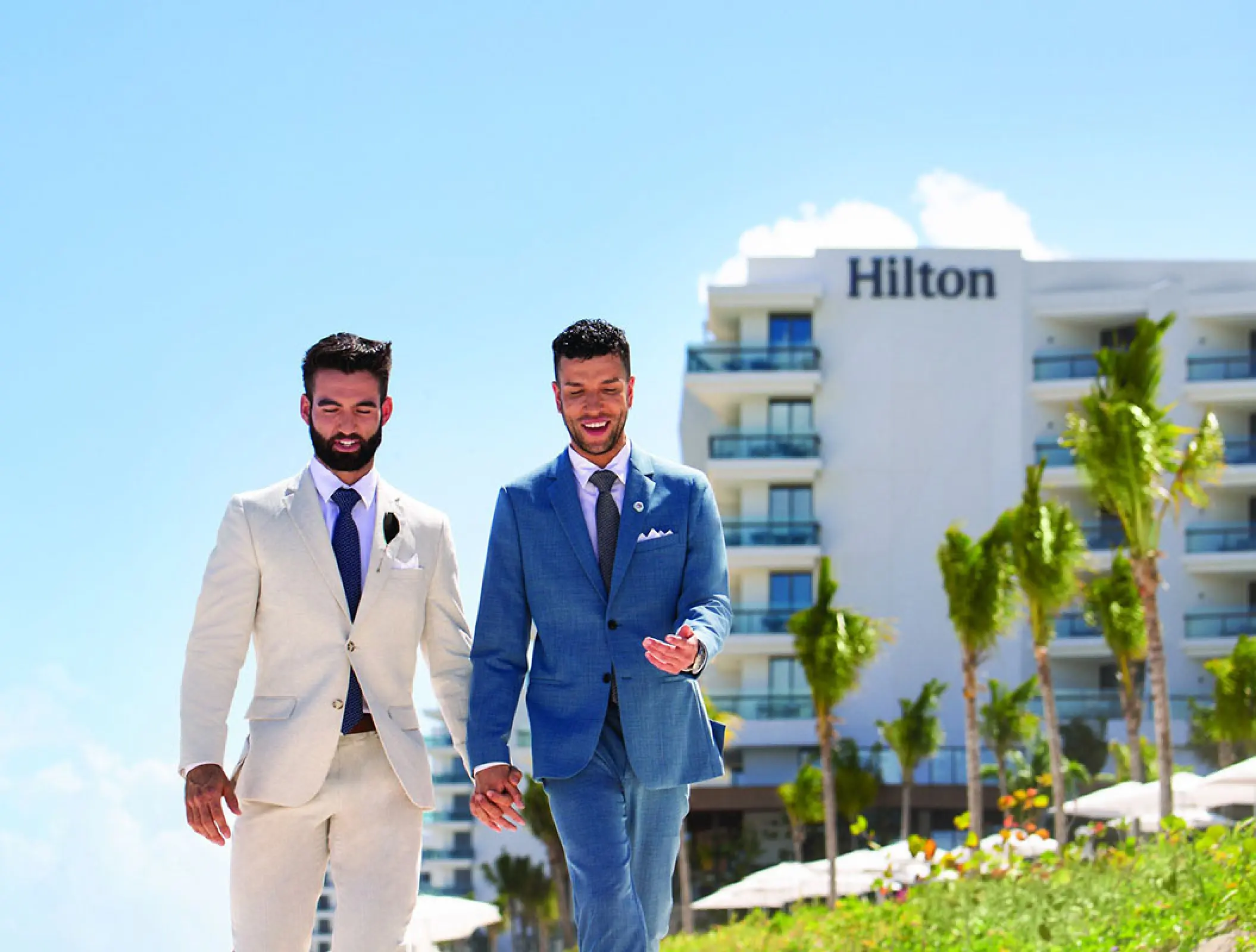 Same-sex couple walking and holding hands outside Hilton Cancun