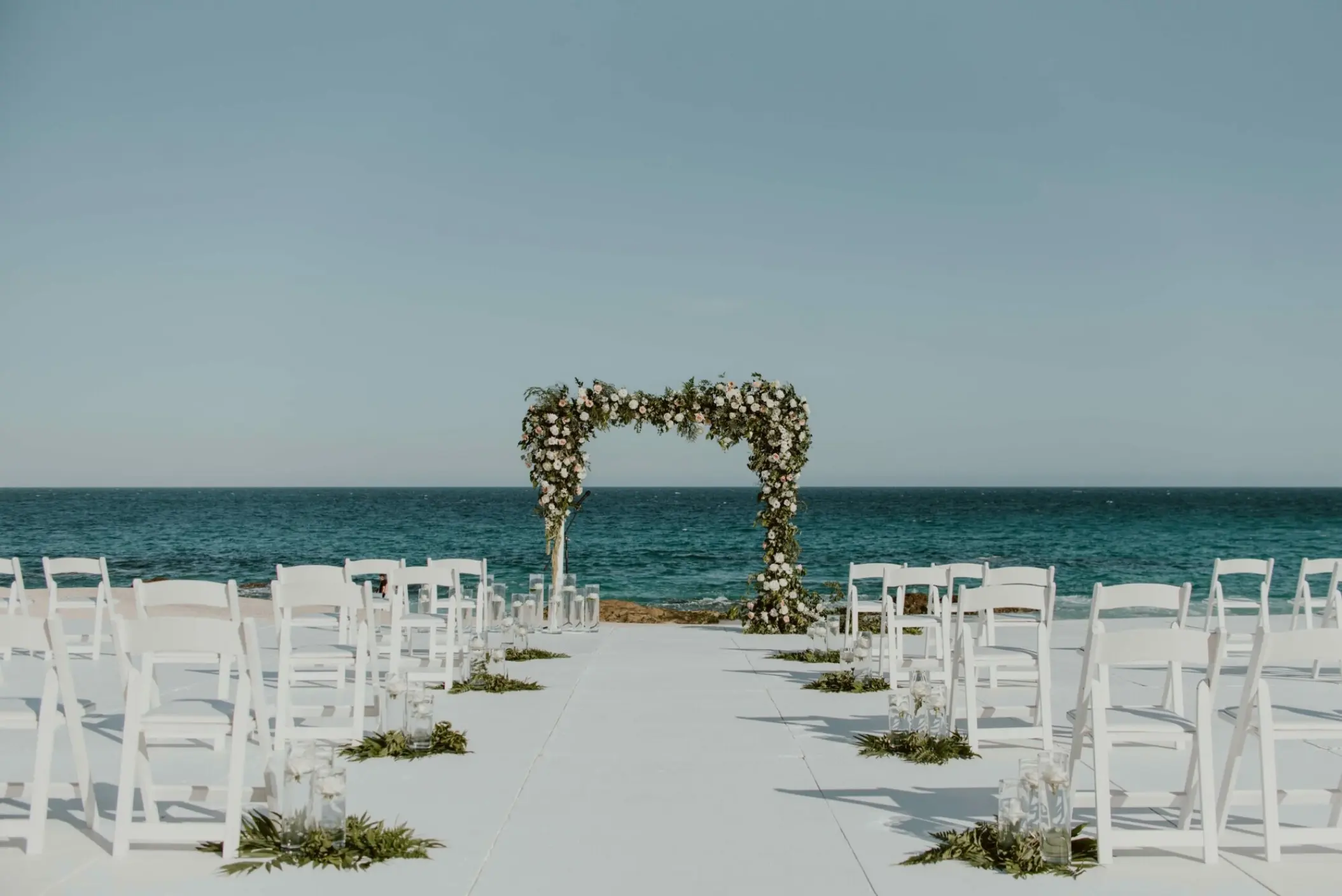 Beachfront wedding ceremony setup with floral arch at Hilton Los Cabos, Cabo San Lucas