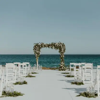 Beachfront wedding ceremony setup with floral arch at Hilton Los Cabos, Cabo San Lucas