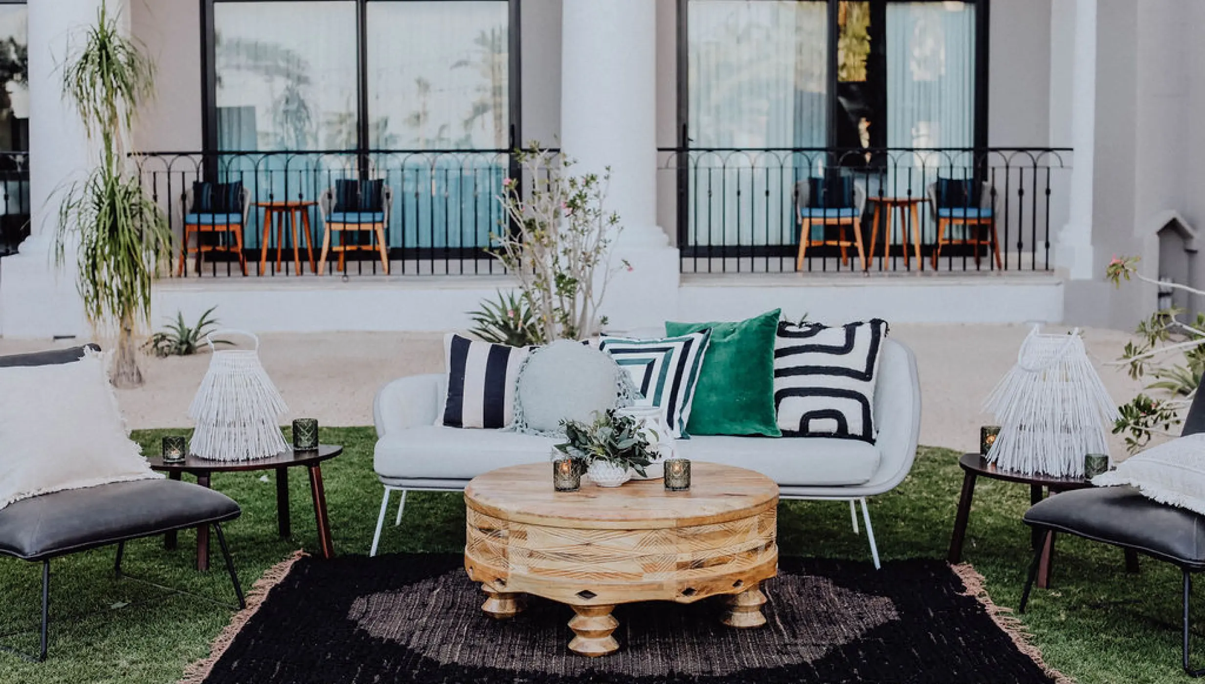 Outdoor lounge area with modern sofas and wooden tables for a wedding reception at Hilton Los Cabos, Cabo San Lucas