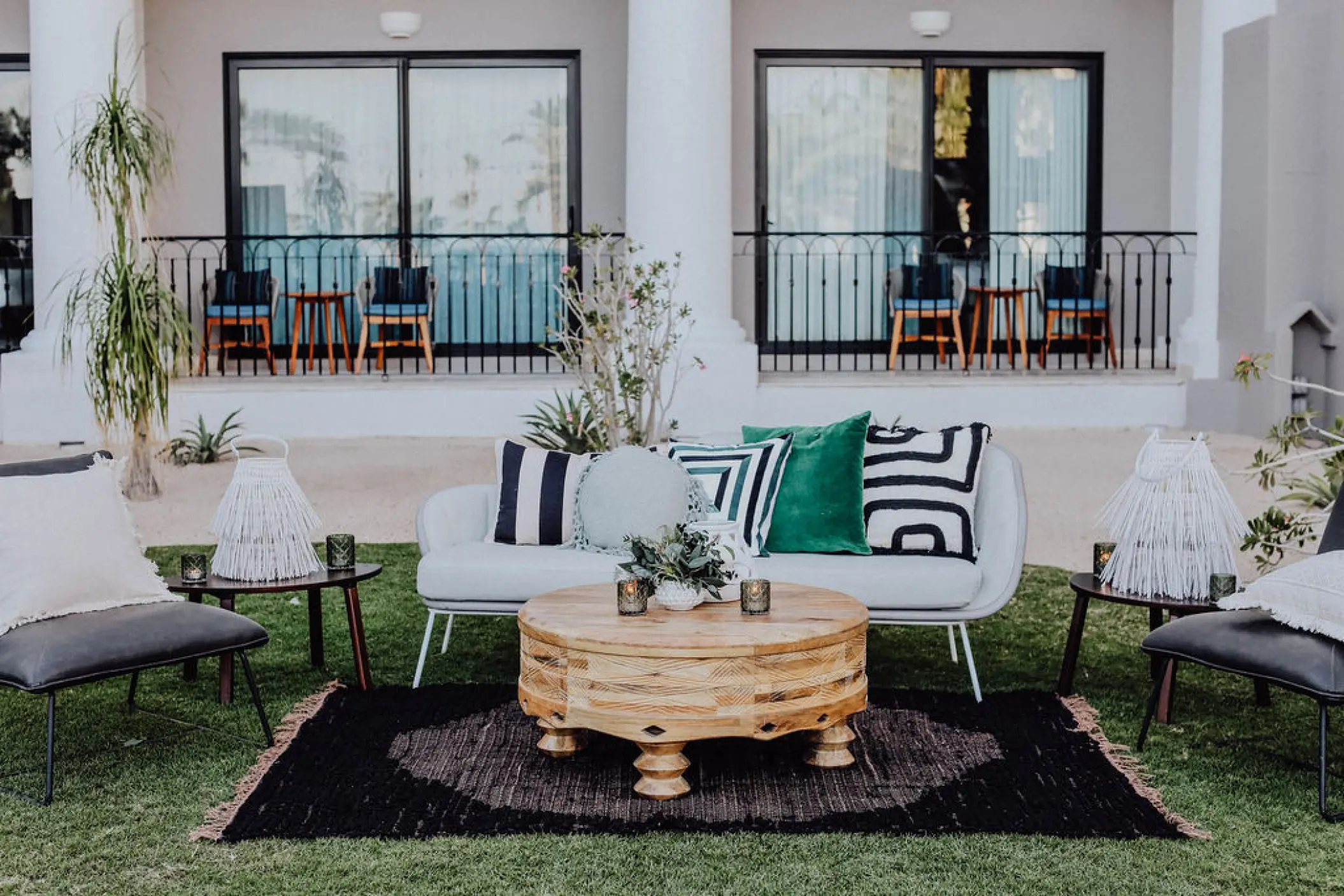 Outdoor lounge area with modern sofas and wooden tables for a wedding reception at Hilton Los Cabos, Cabo San Lucas
