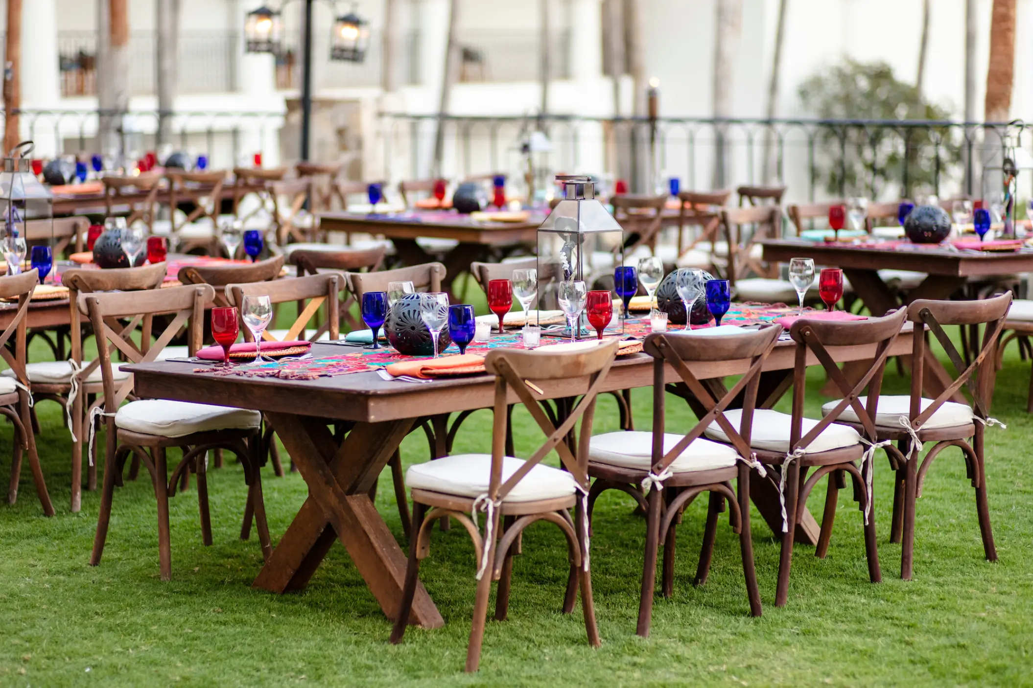 Outdoor wedding reception with wooden cross-back chairs on the lawn at Hilton Los Cabos, Cabo San Lucas