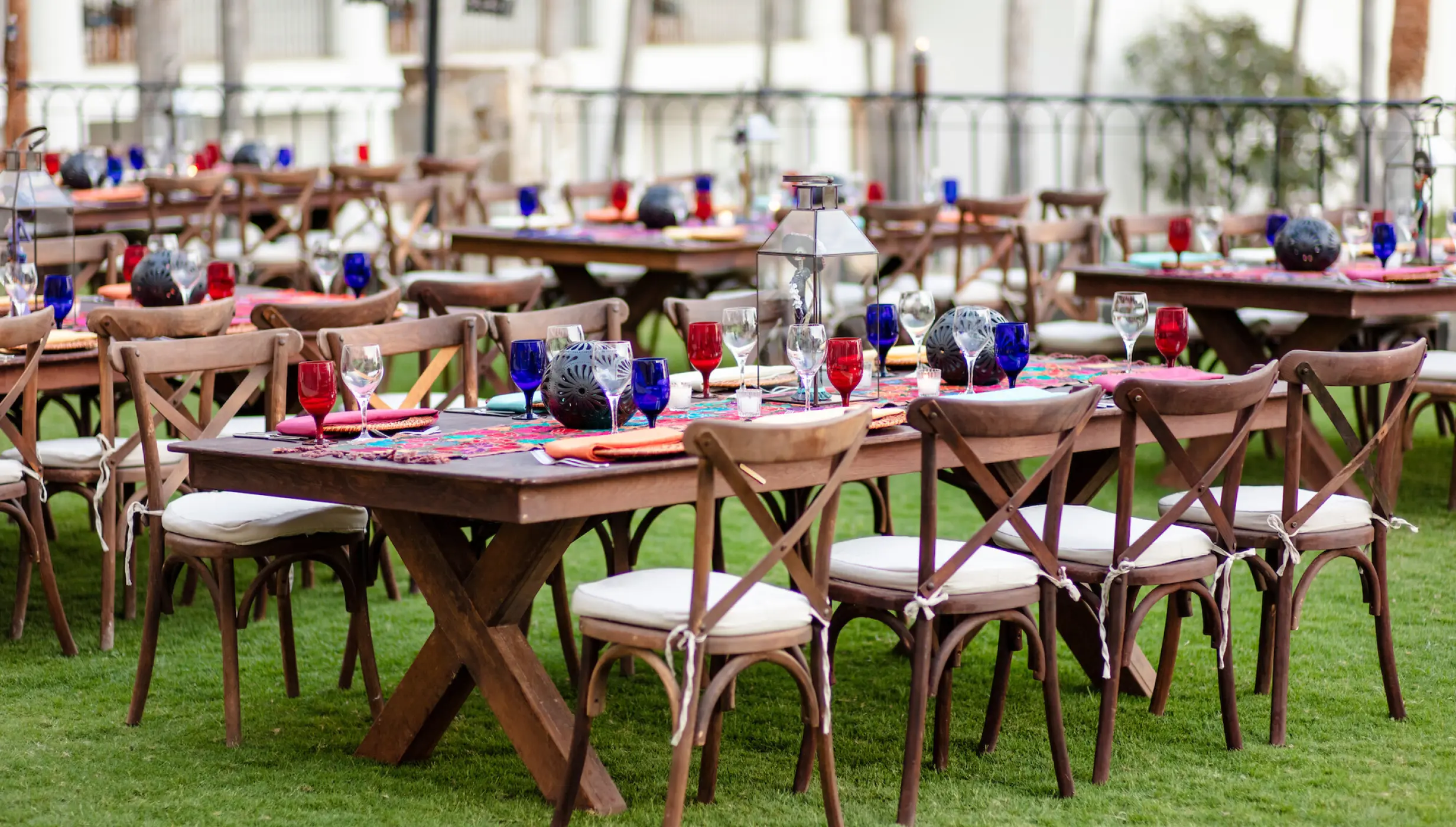 Outdoor wedding reception with wooden cross-back chairs on the lawn at Hilton Los Cabos, Cabo San Lucas