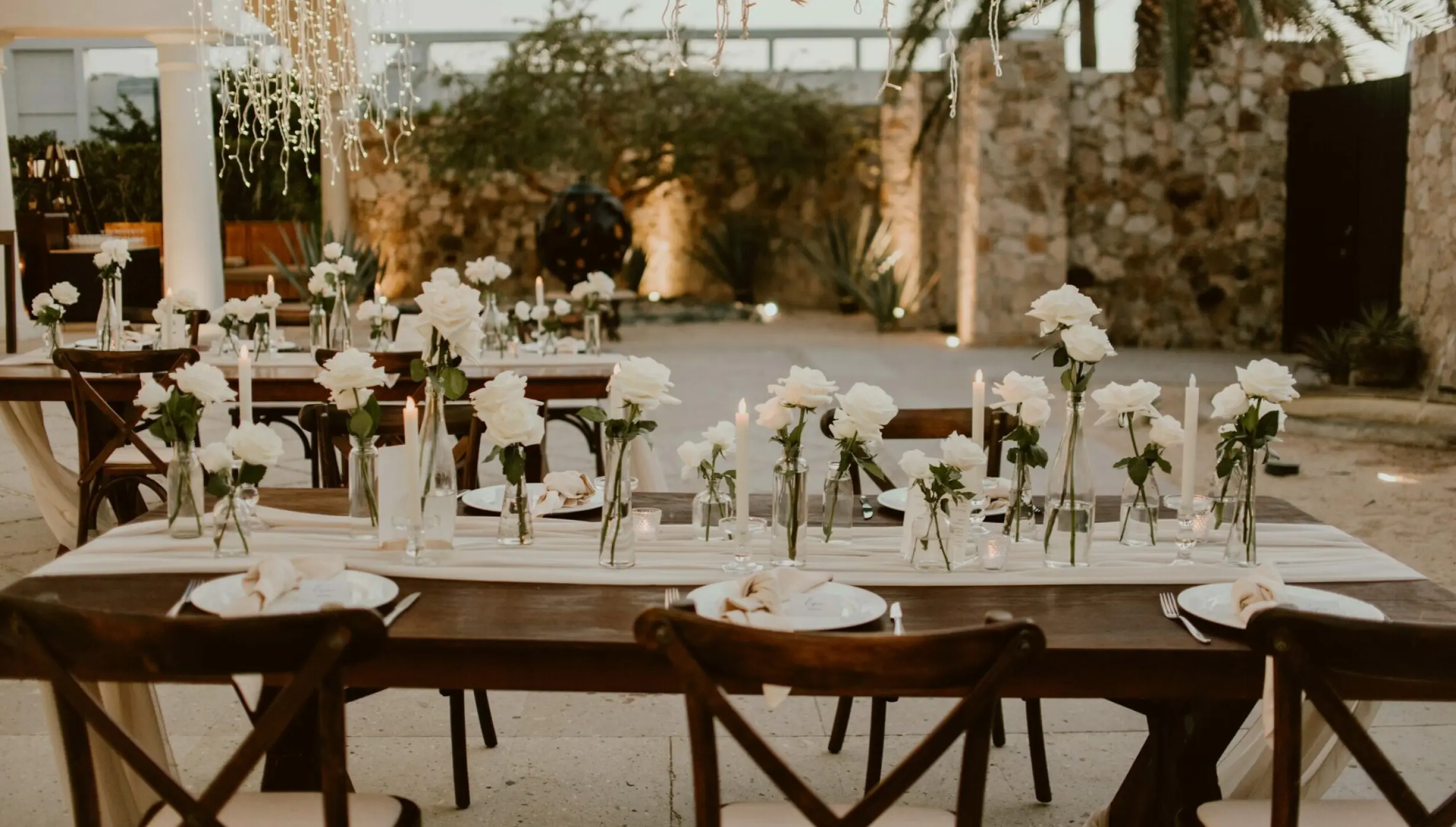 Outdoor wedding reception tables with white roses and cross-back chairs at Hilton Los Cabos, Cabo San Lucas