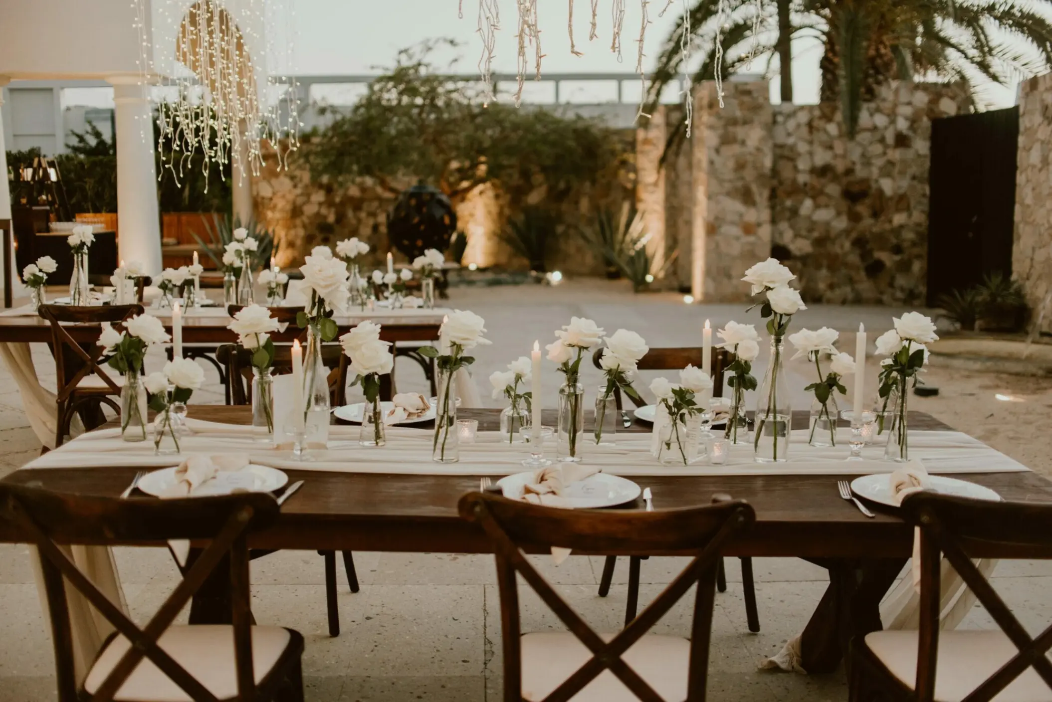 Outdoor wedding reception tables with white roses and cross-back chairs at Hilton Los Cabos, Cabo San Lucas