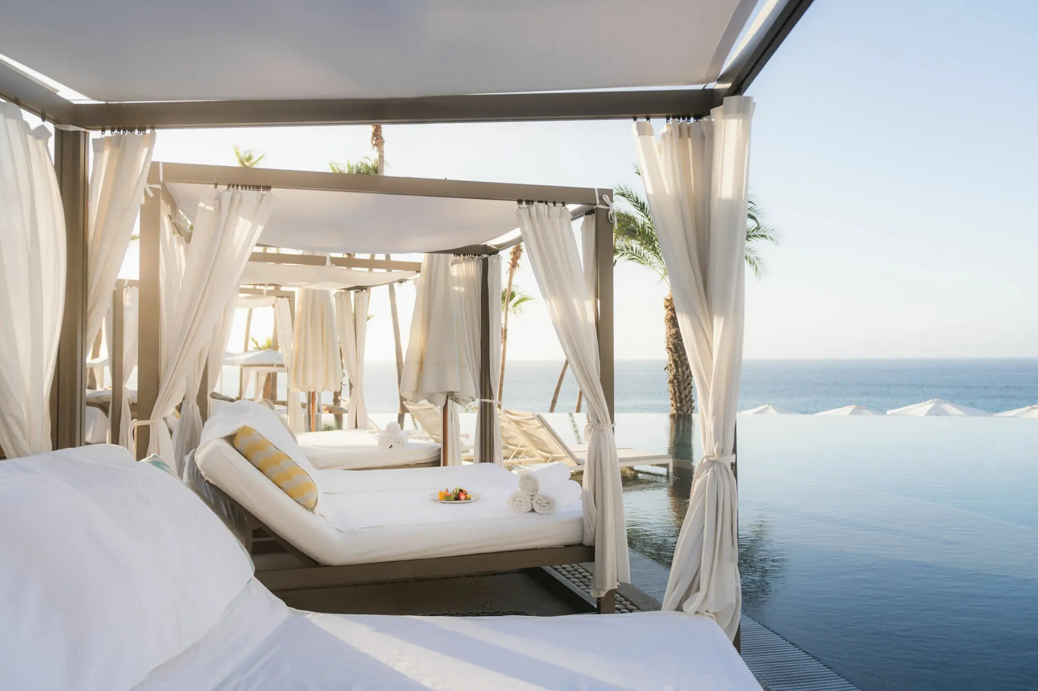 Poolside cabanas with white daybeds beside the infinity pool at Hilton Los Cabos, Cabo San Lucas