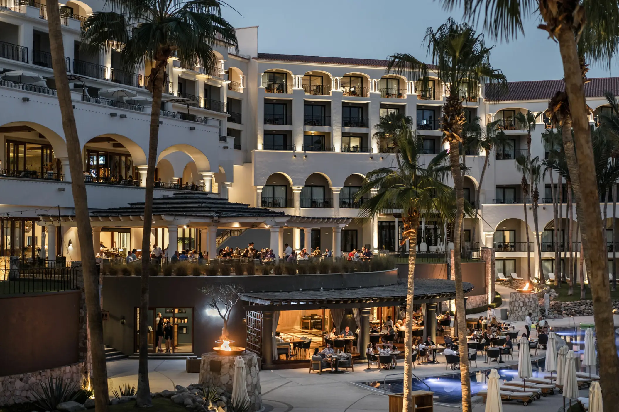 Hilton Los Cabos illuminated exterior and patio dining by the pool at dusk, Cabo San Lucas