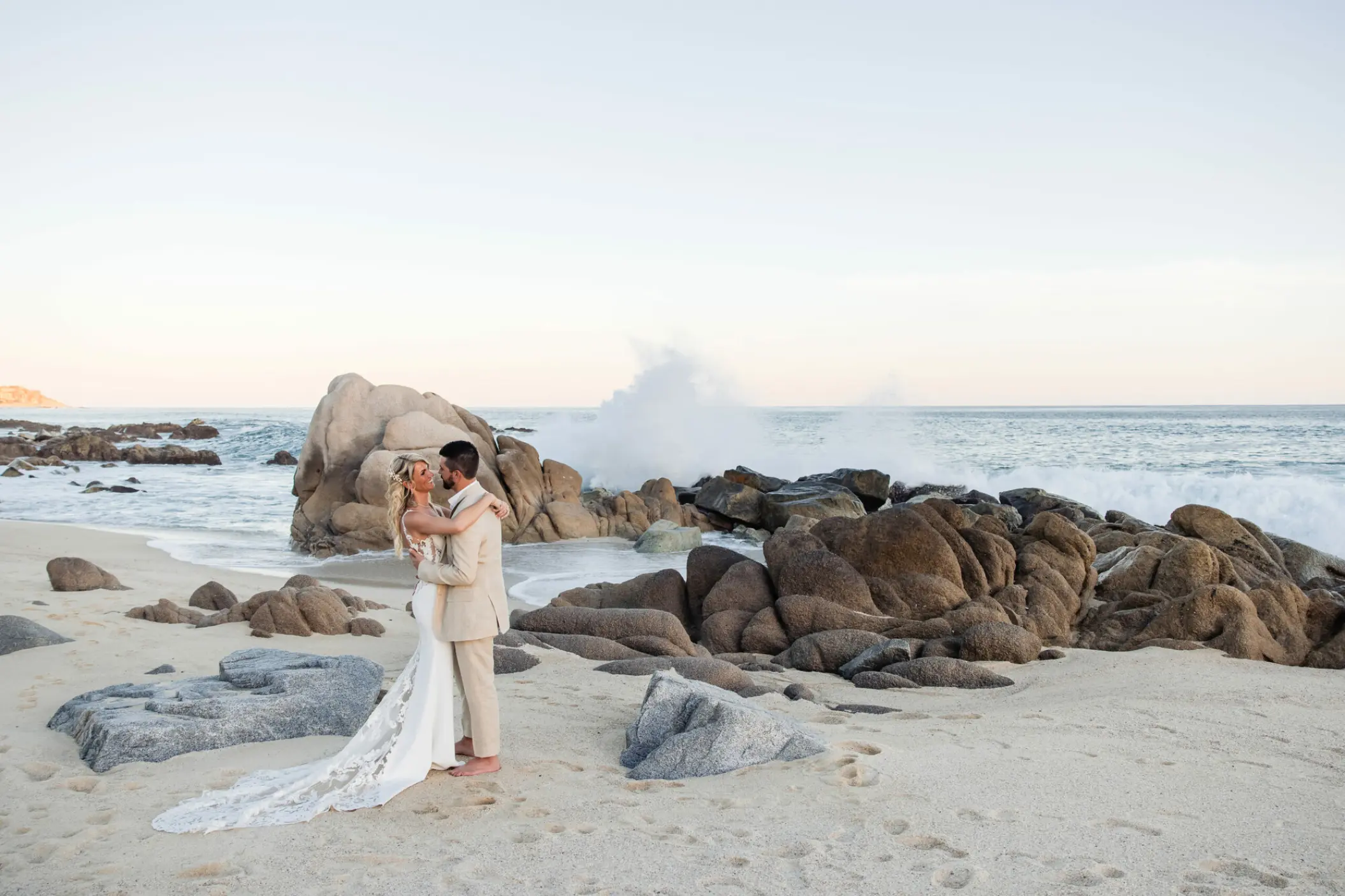 Bride and groom embracing on a rocky beach at Hilton Los Cabos, Cabo San Lucas