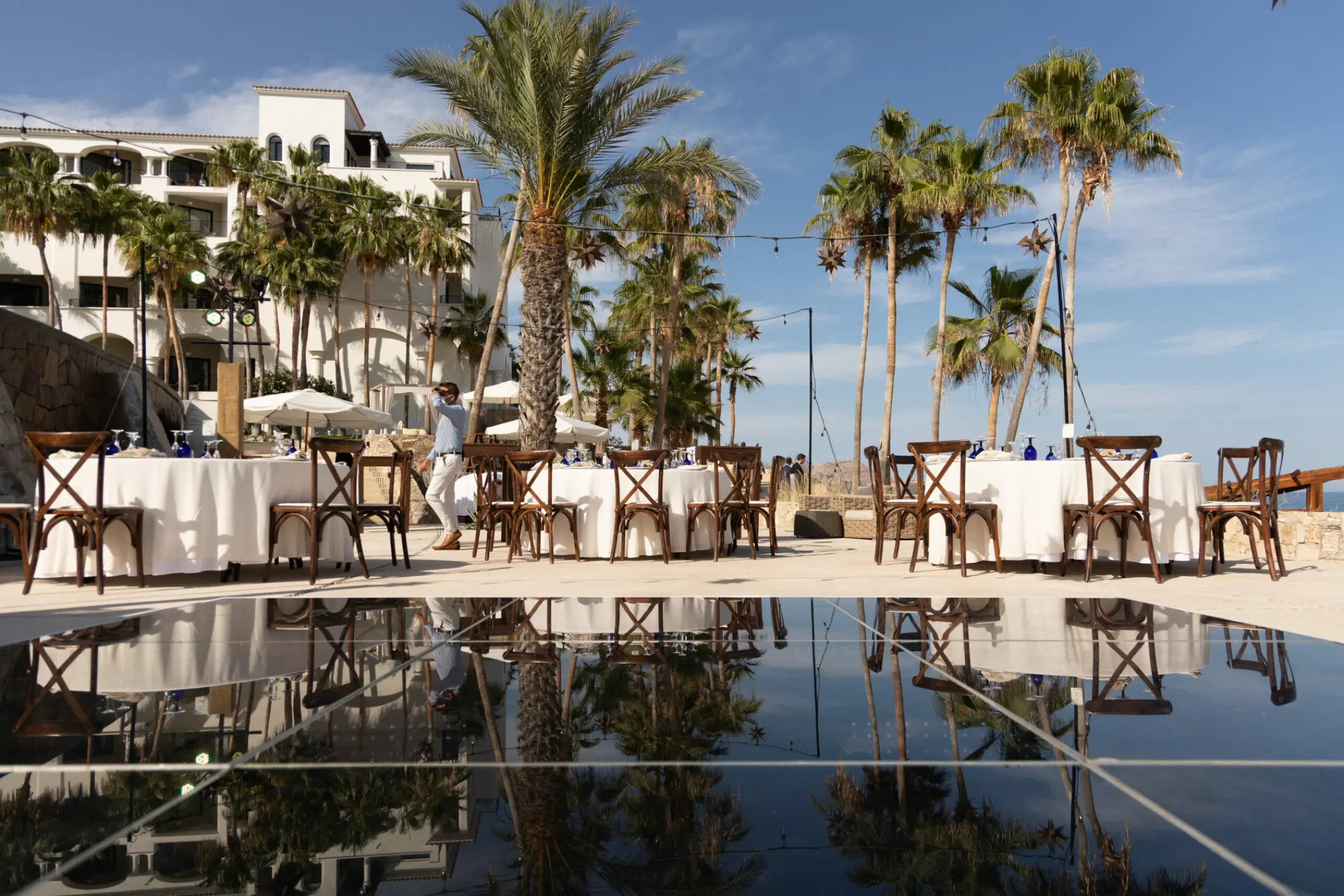 Wedding reception tables with cross-back chairs on the Whale Watching Terrace at Hilton Los Cabos, Cabo San Lucas
