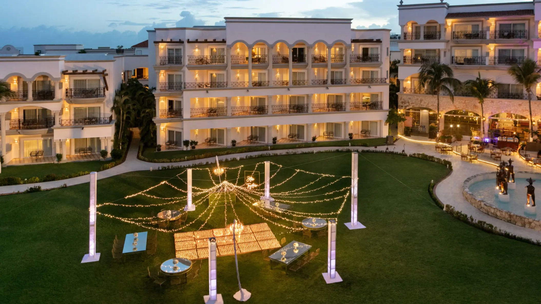 Outdoor wedding reception setup with string lights on the lawn at Hilton Playa del Carmen