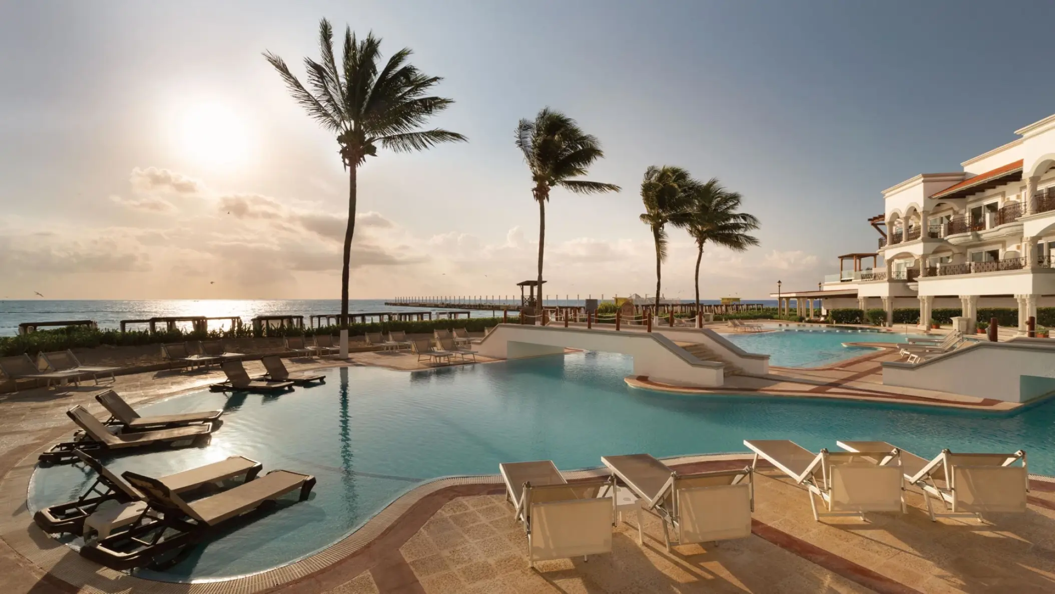 Beachfront infinity pool with lounge chairs and palm trees at Hyatt Vivid Playa del Carmen