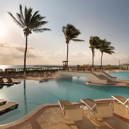 Beachfront infinity pool with lounge chairs and palm trees at Hyatt Vivid Playa del Carmen