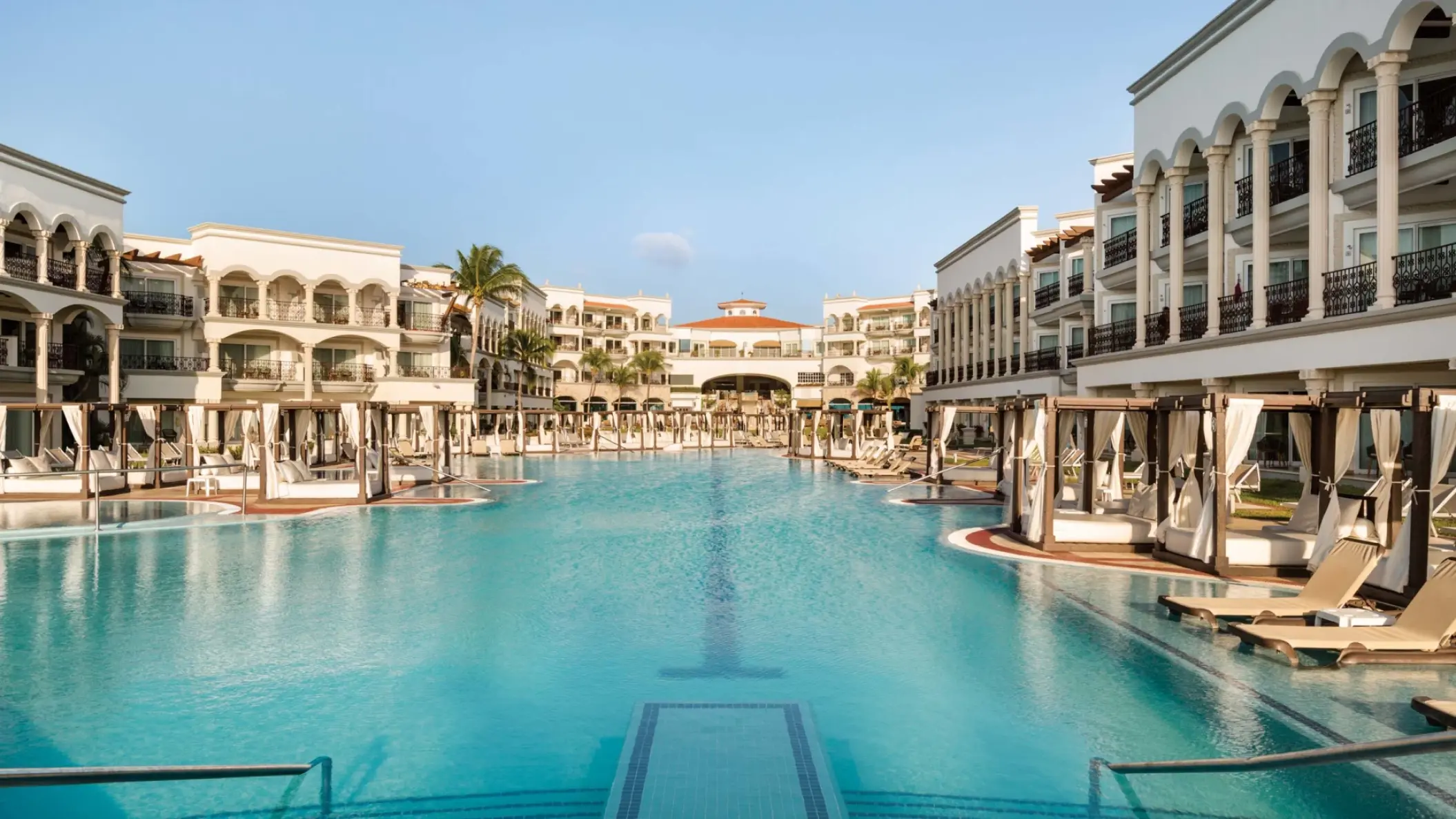 Main pool surrounded by white buildings and cabanas at Hilton Playa del Carmen, Playa Del Carmen