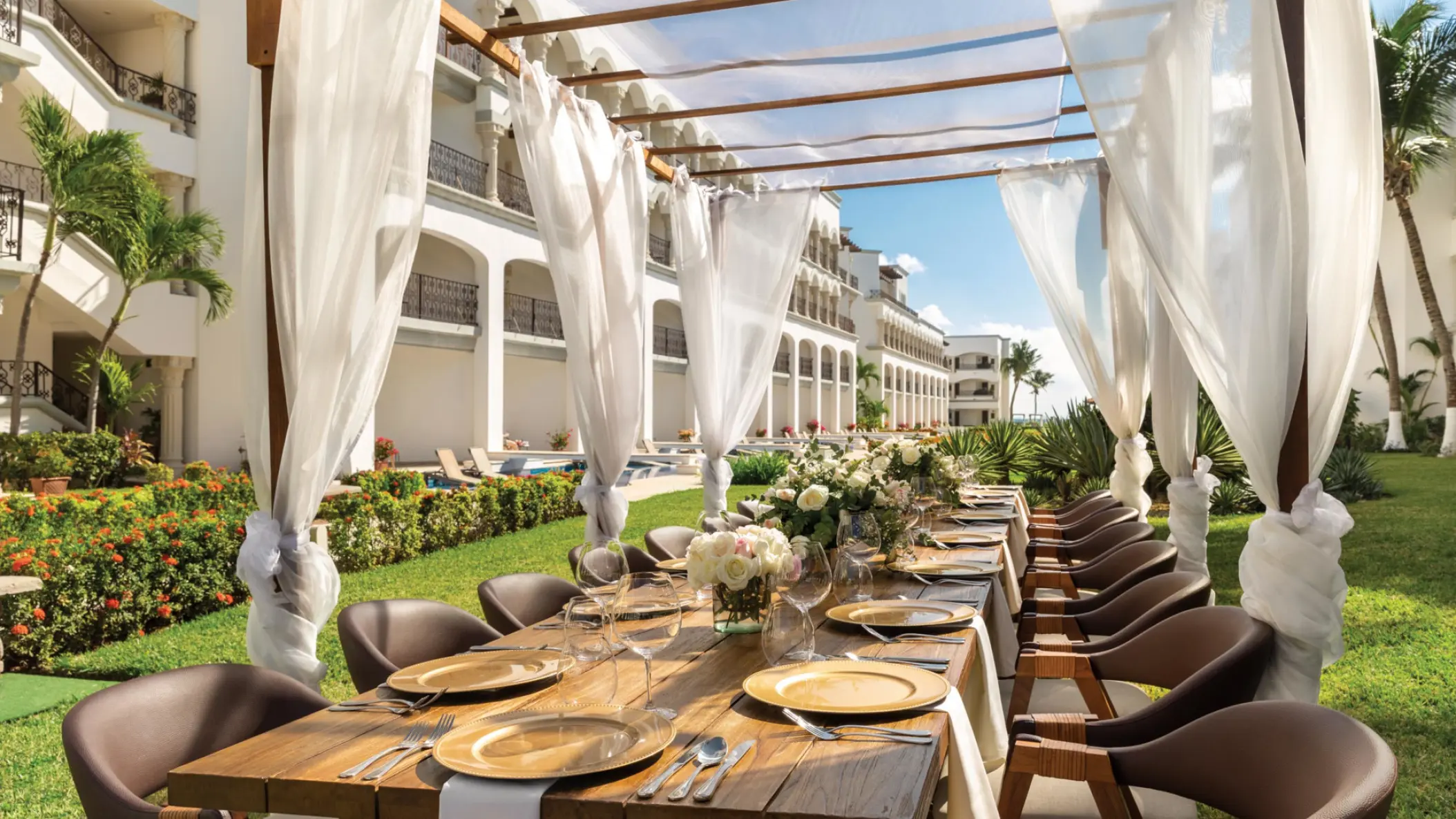 Outdoor garden wedding reception under a draped pergola at Hilton Playa del Carmen